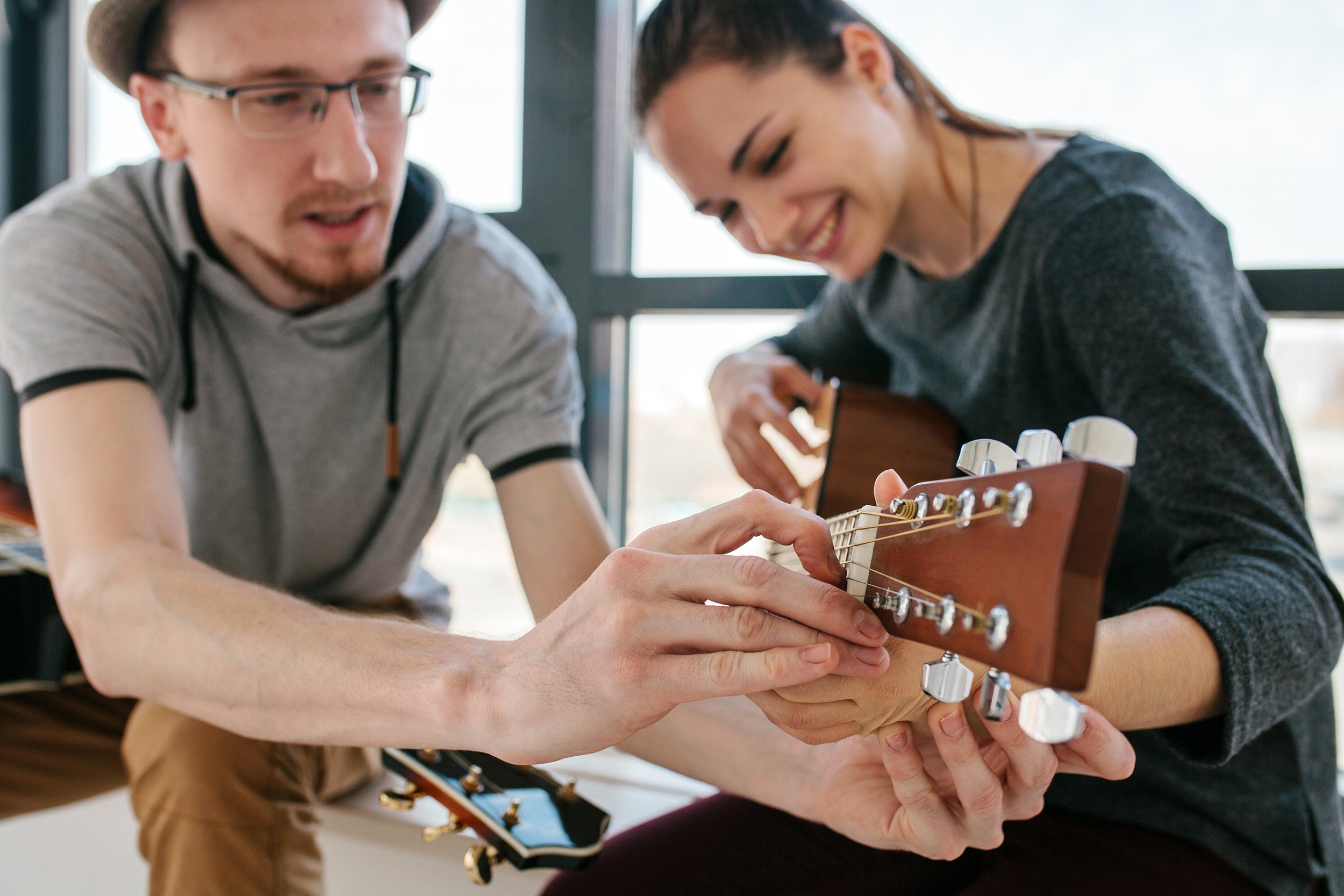 Young man teaching young woman to play guitar