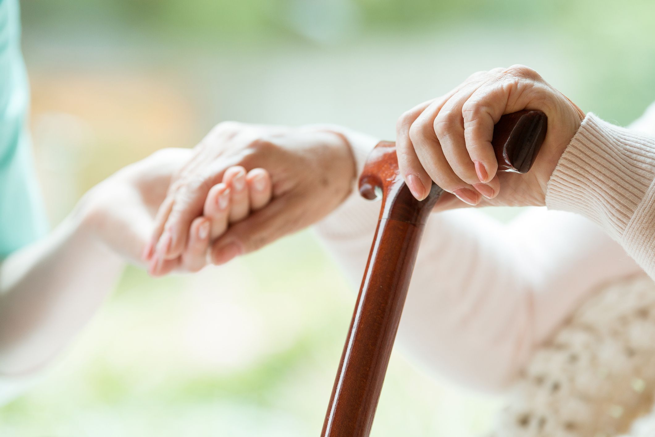 younger hand holding senior hand with cane