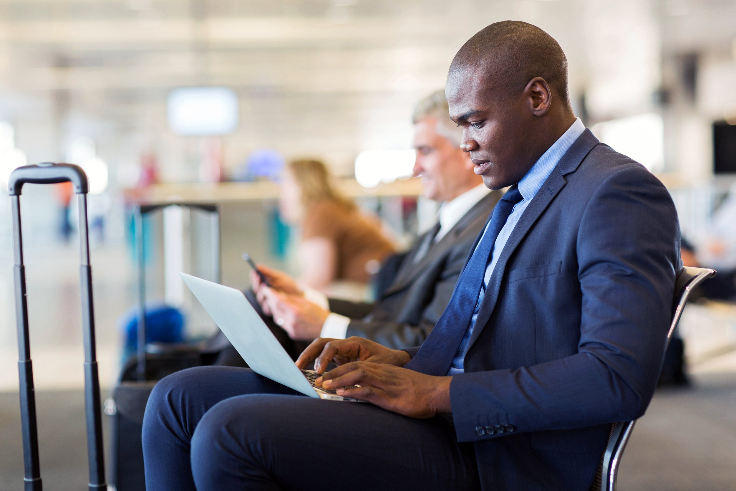 Businessman sitting in airport using his laptop