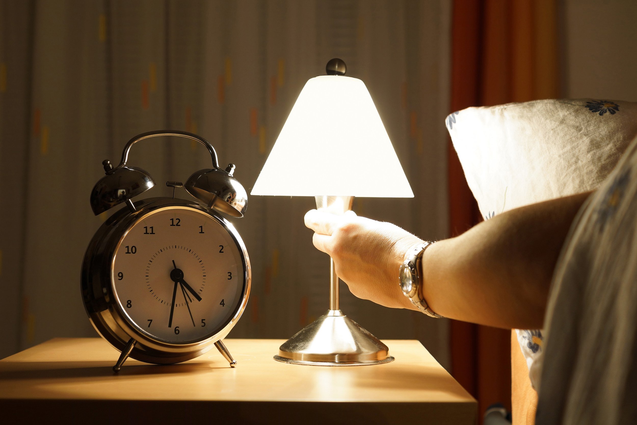 Person turning off lamp from bed