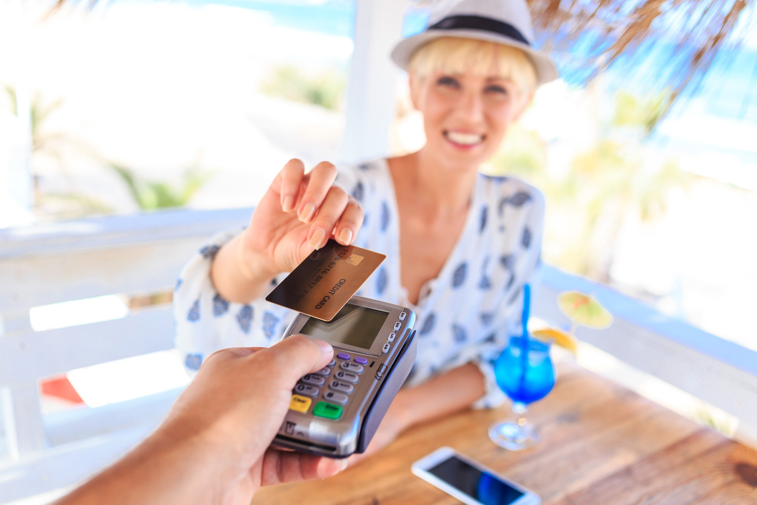 Woman purchasing drink with credit card on vacation