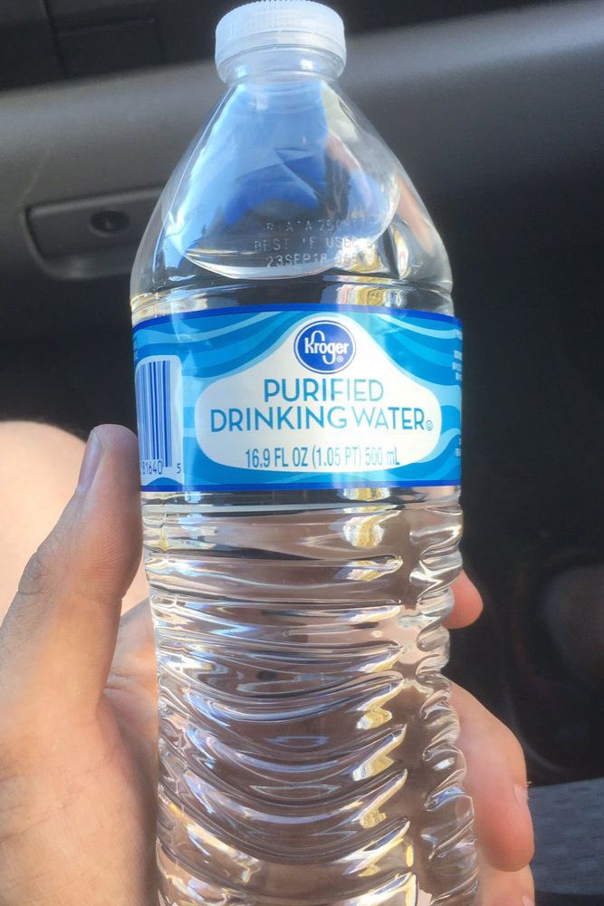 hand holding Kroger purified water in car