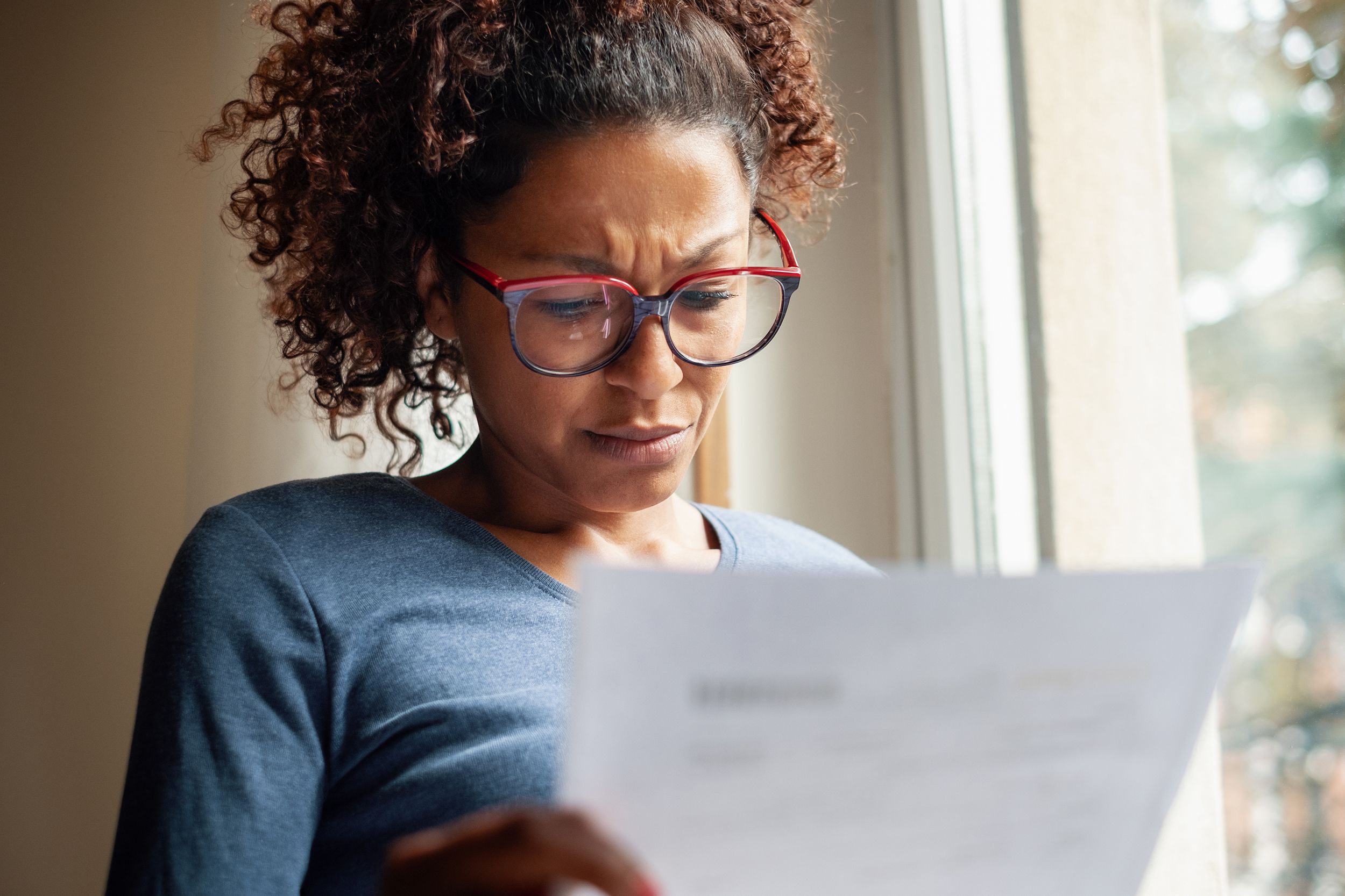 woman near window reading bad news letter