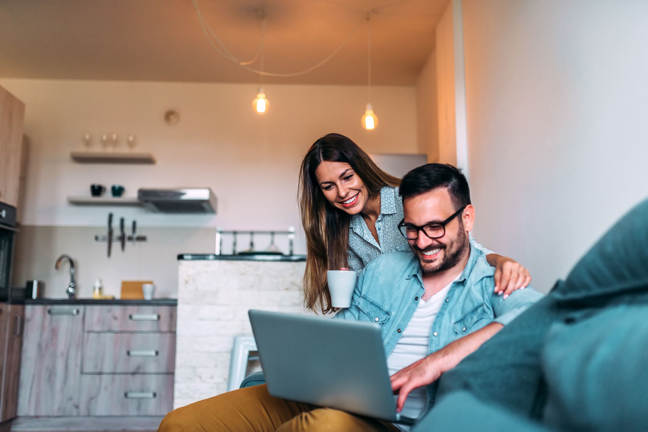 young couple using a laptop while sitting on the sofa at home