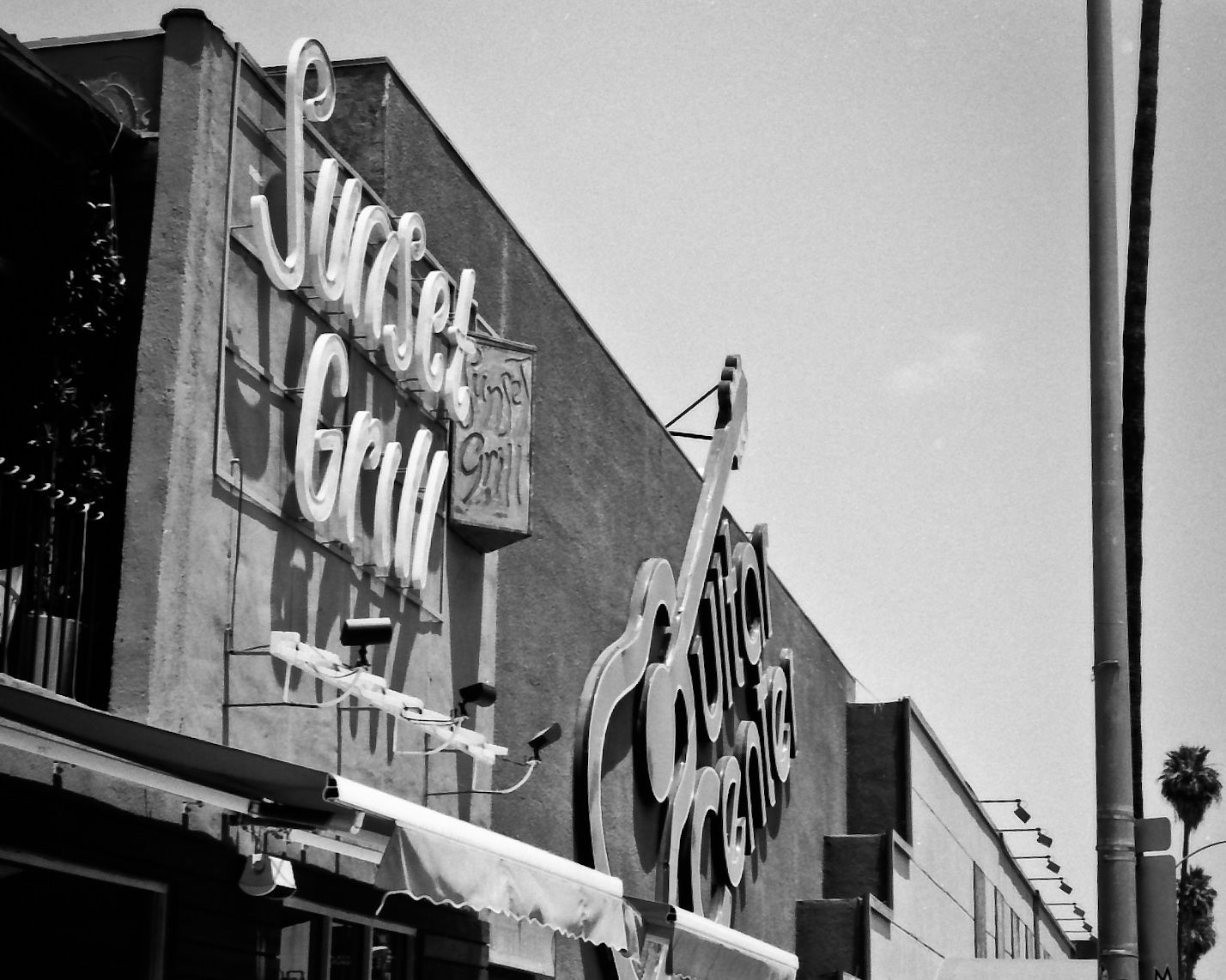 sunset grill sign next to guitar center sign, side angle from street