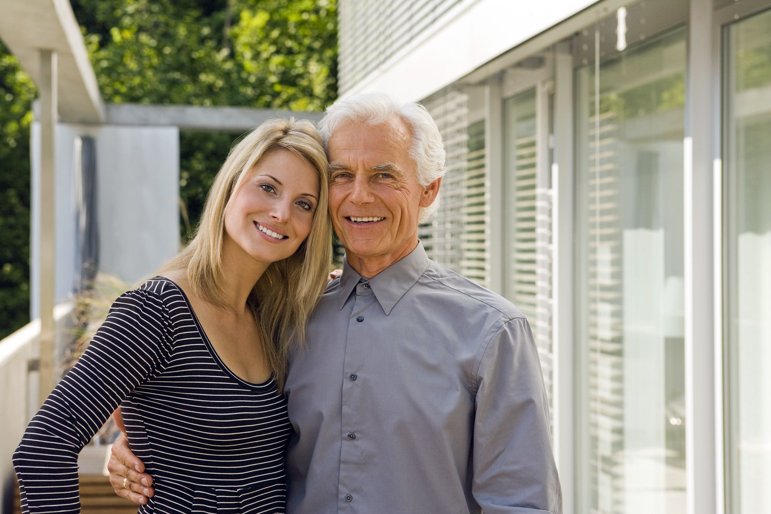 Older man and younger wife smiling at camera