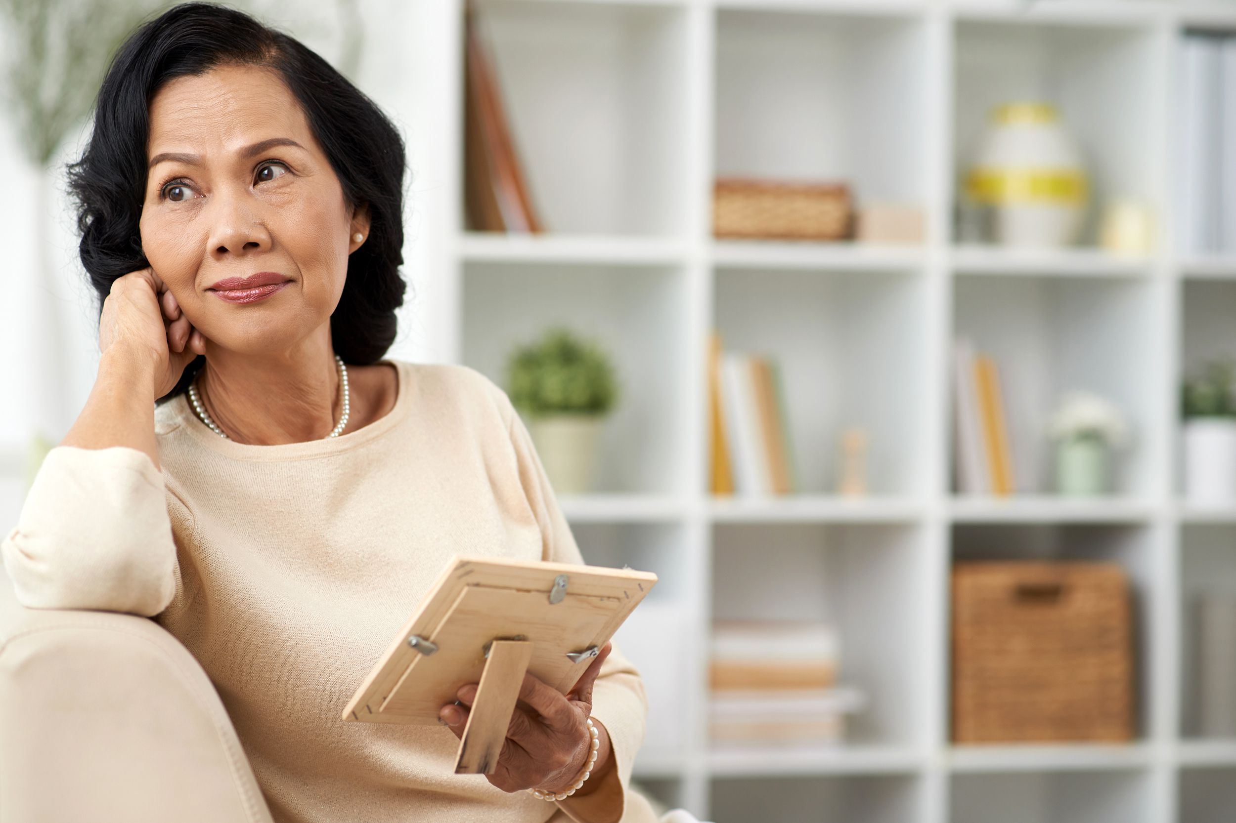Widow thinking about her late spouse and holding a picture frame
