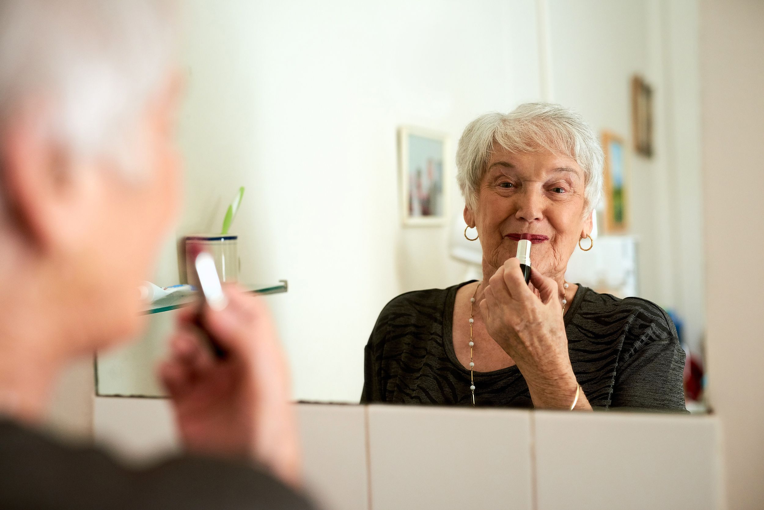 Senior woman putting on lipstick
