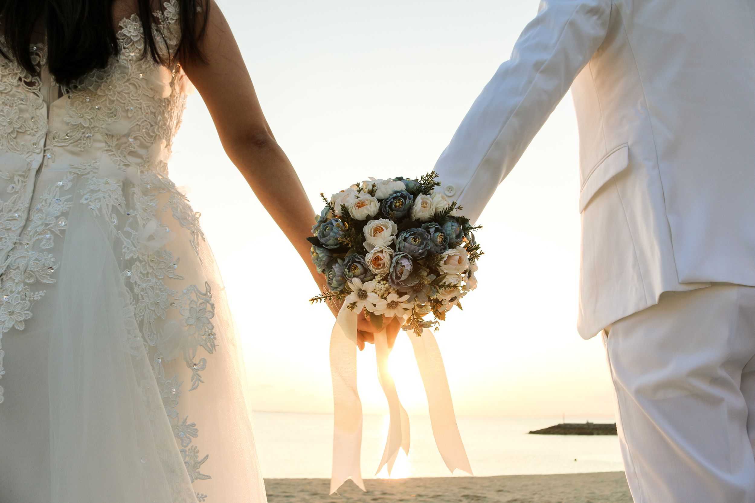 Closeup of bouquet and married couple on the beach