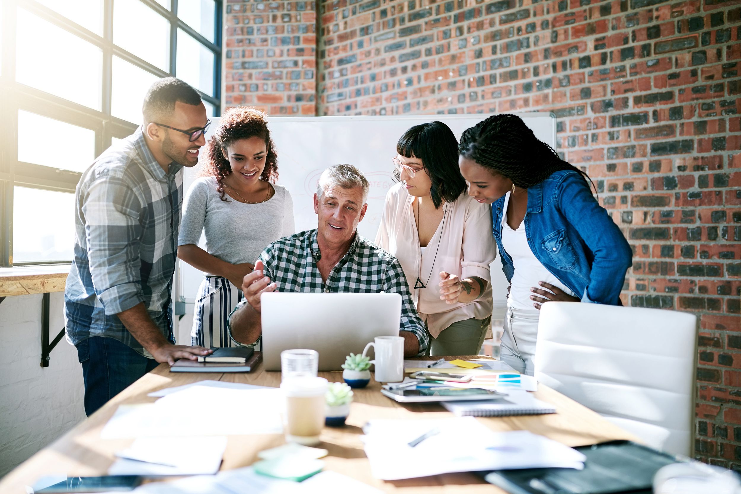group discussing together around laptop in meeting room