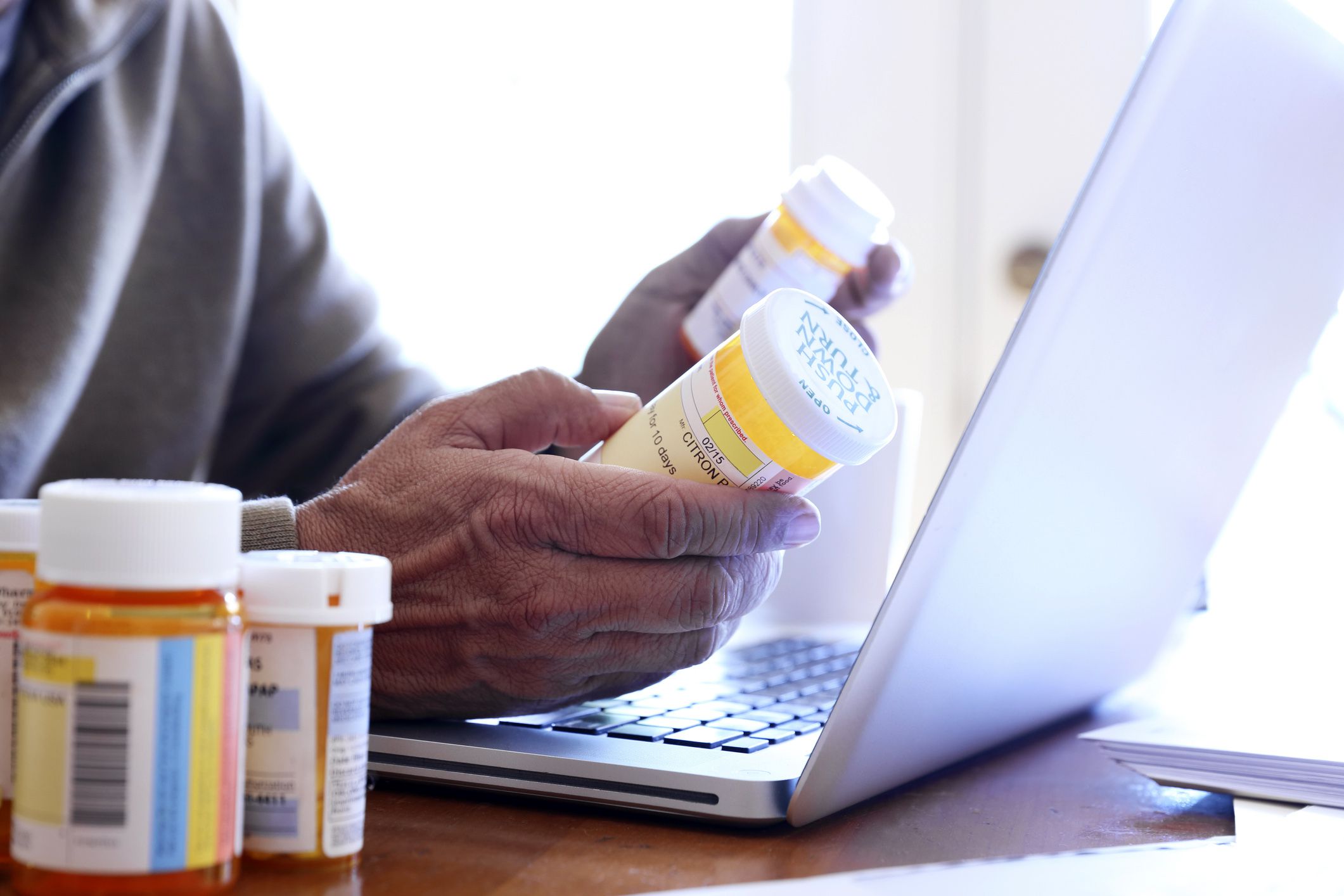 hands looking at prescriptions and laptop