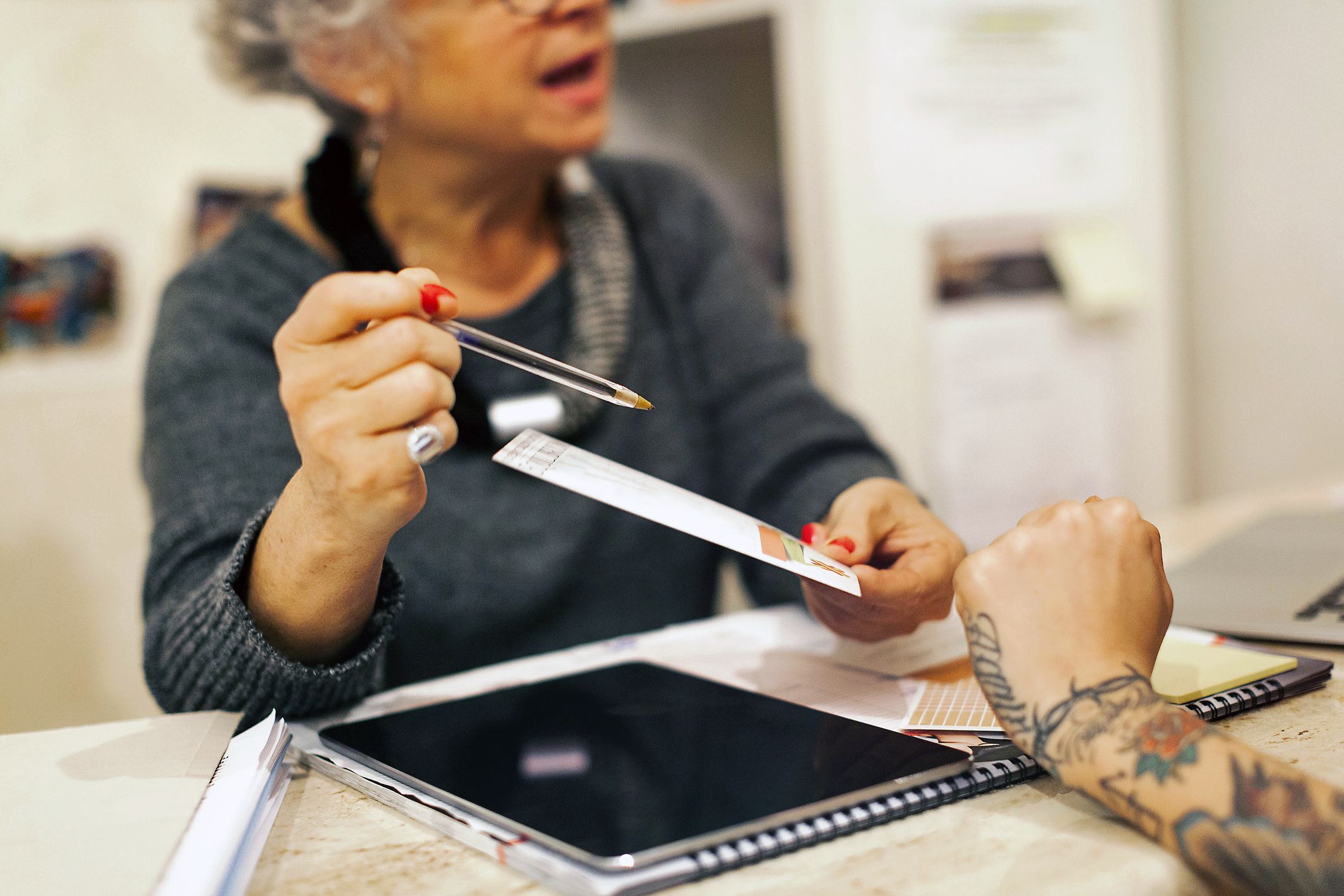 senior woman secretary shows brochure to patient, close-up of hands