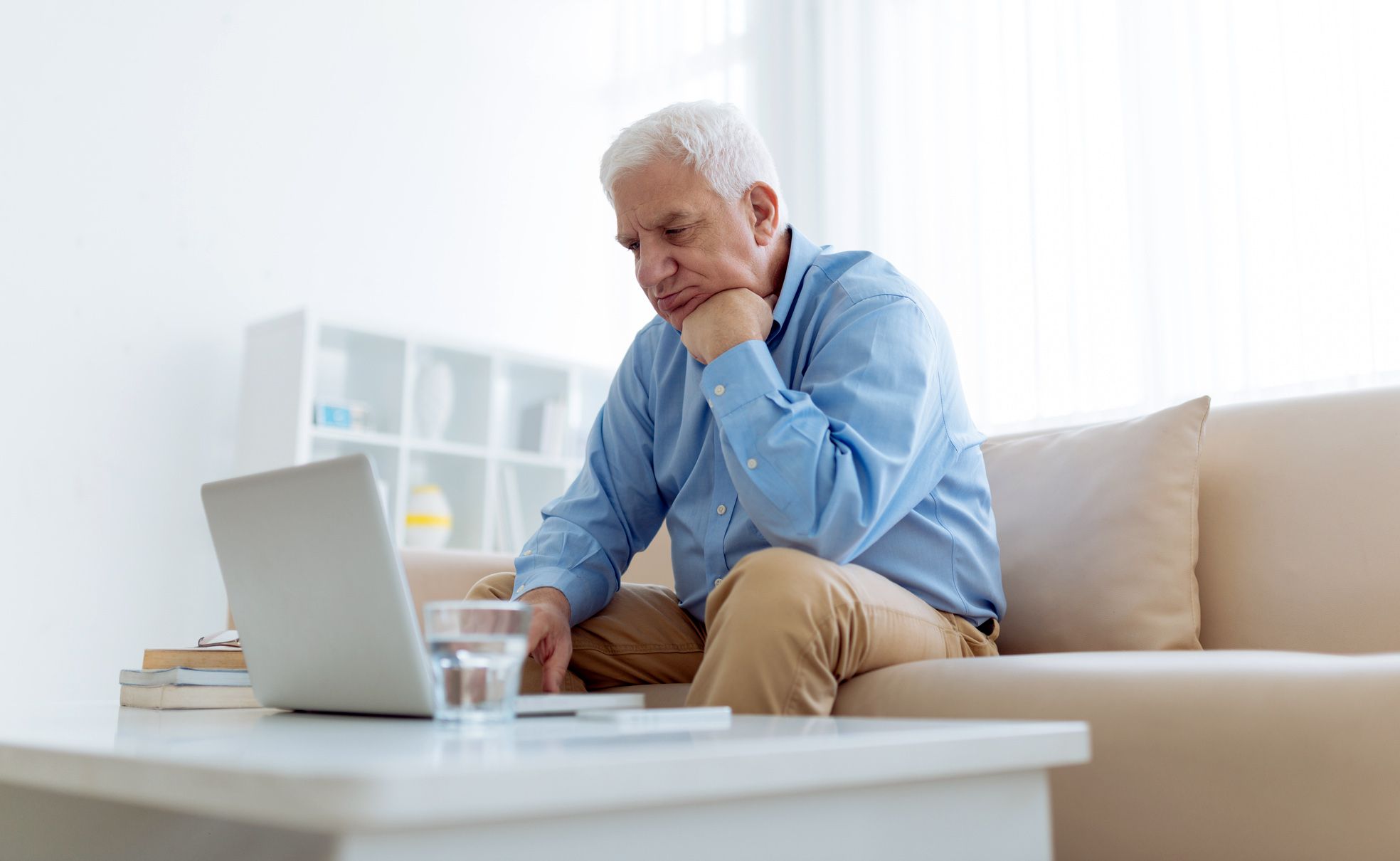 senior man sitting on couch looking at computer