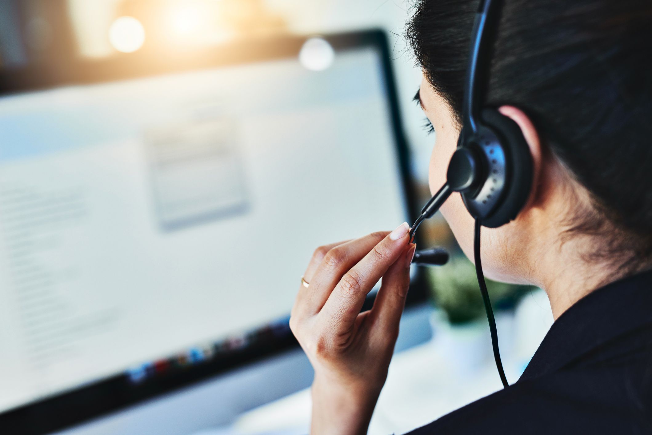 woman with headset in front of computer looking at computer screen