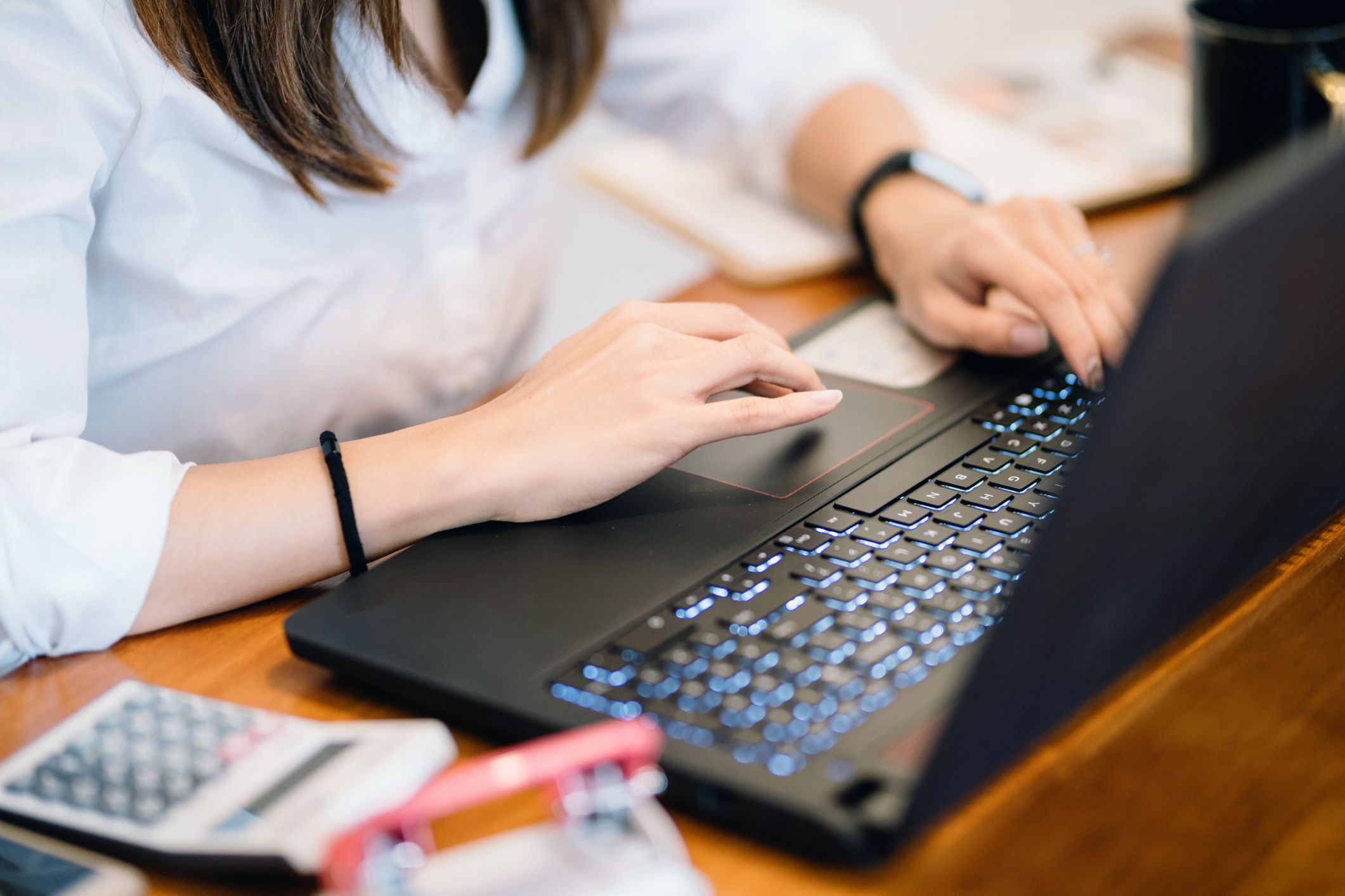 hands typing on laptop, computer to the side