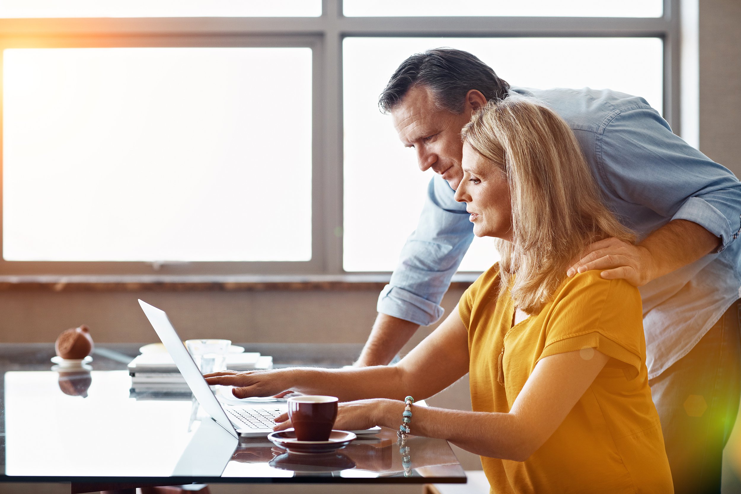 couple at desk in home, looking at laptop