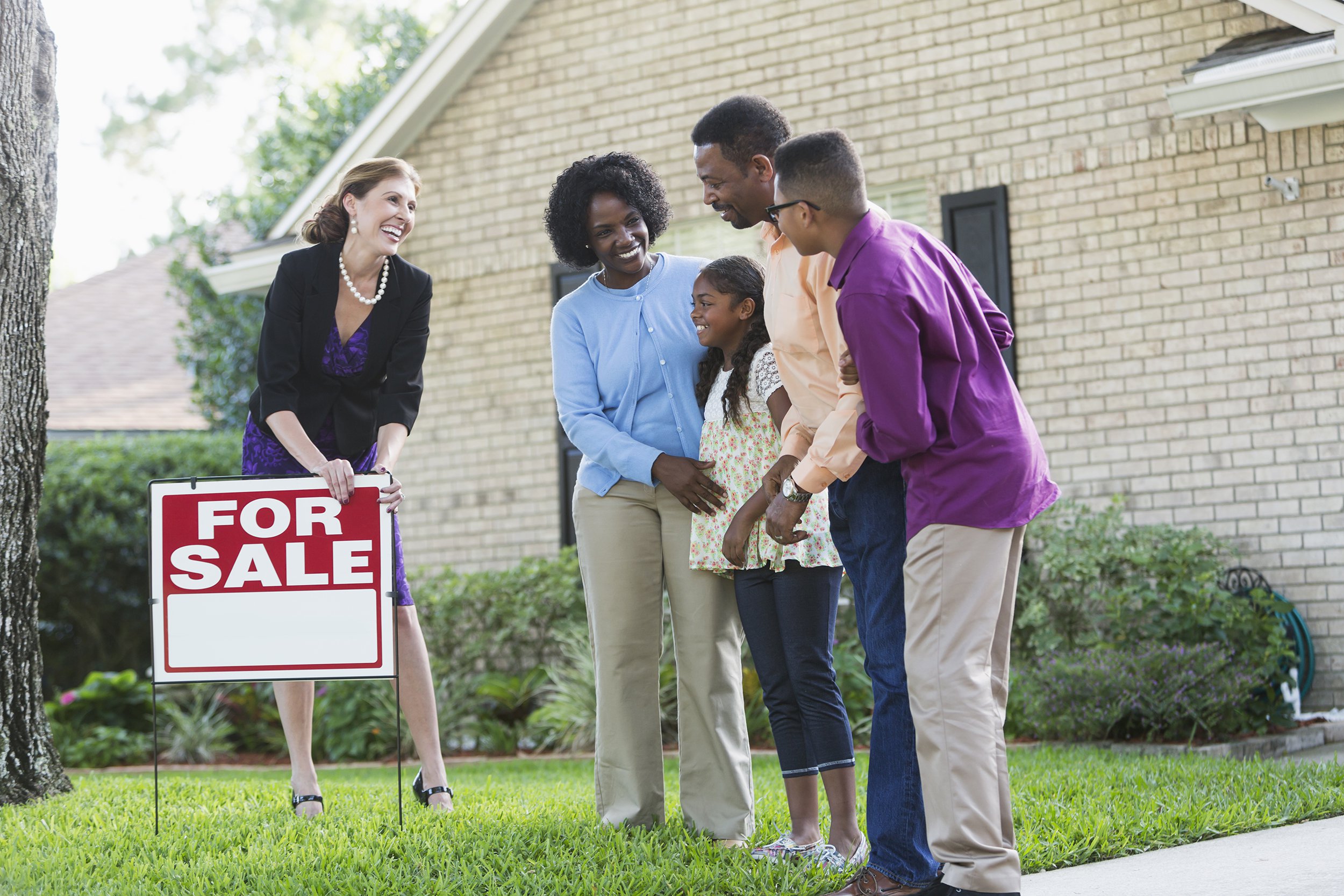 realtor with black family in front of house for sale