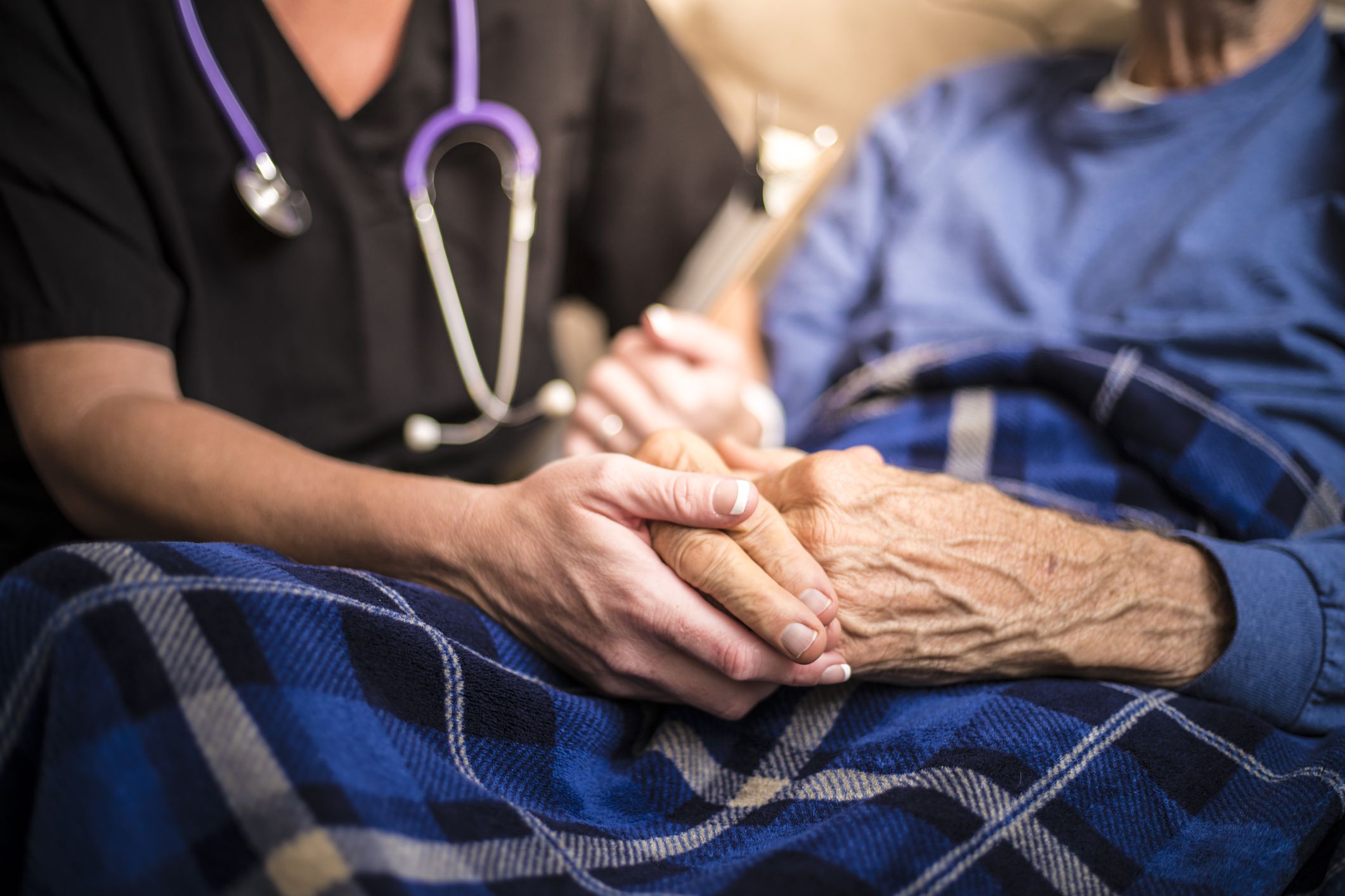 man in hospital bed with nurse holding hands