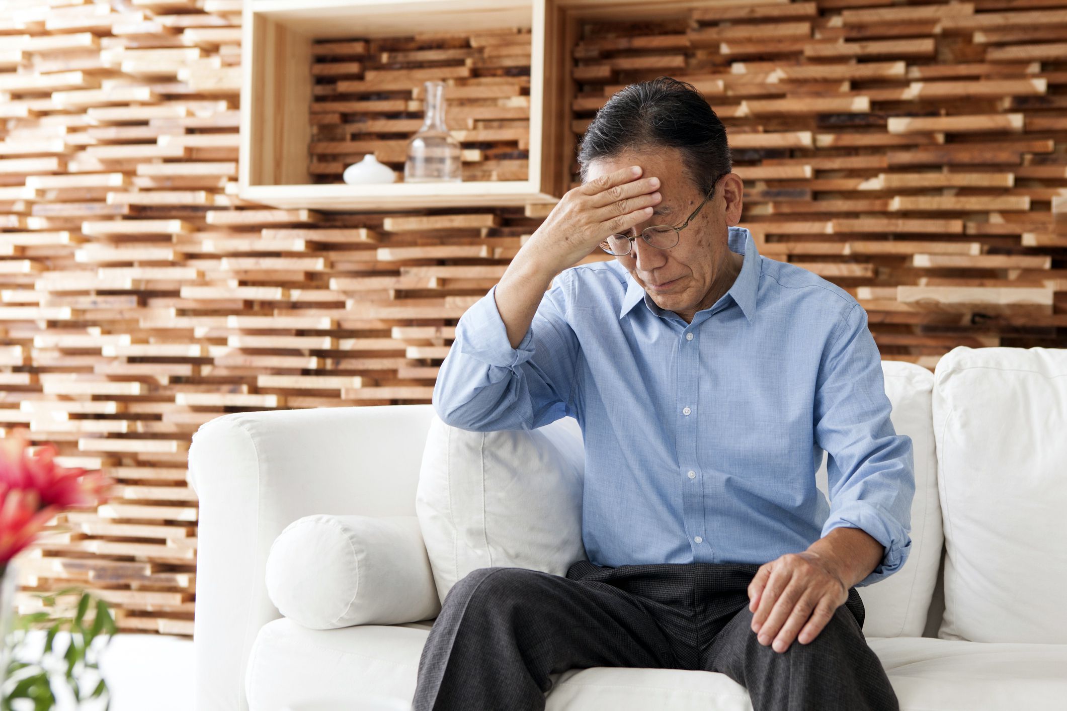 man in 50s sitting on couch looking confused