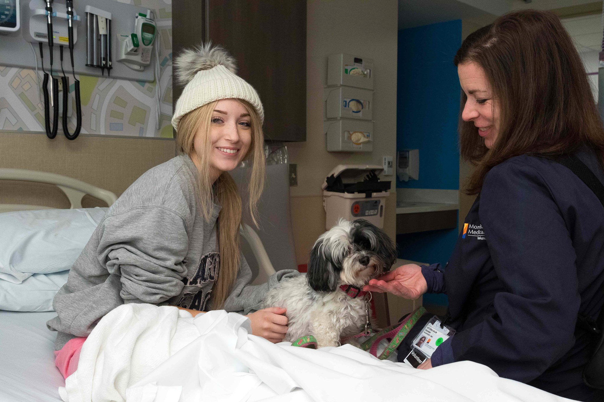 Atlantic Health employee with her dog and a patient in the hospital