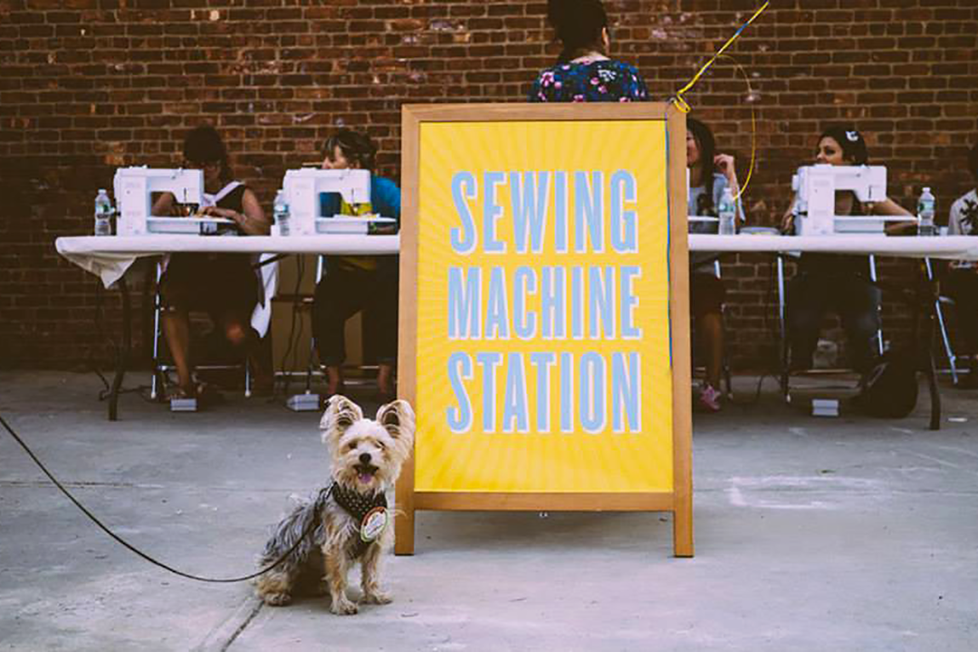 Dog on a leash outside in front of a sign for an Etsy office event