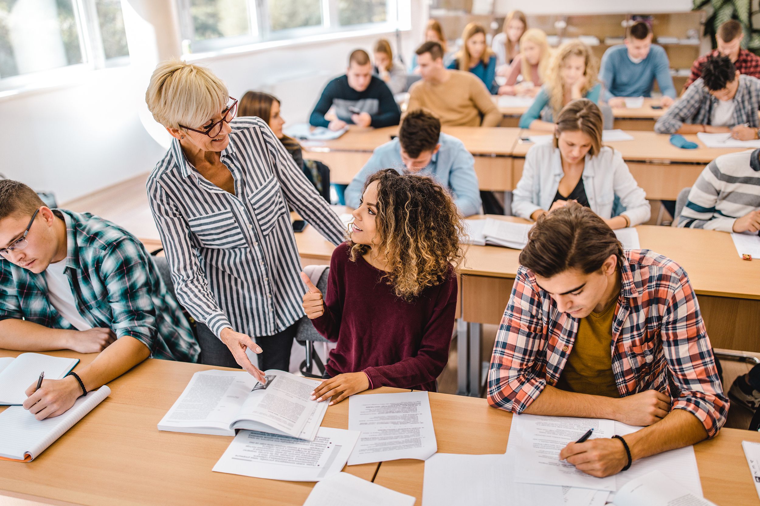 happy female college student talking to senior professor on a class in the classroom