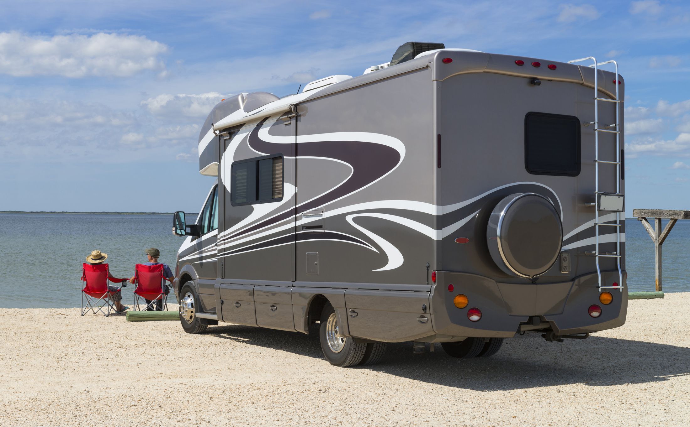 rv overlooking water and two people sitting in chairs looking at water