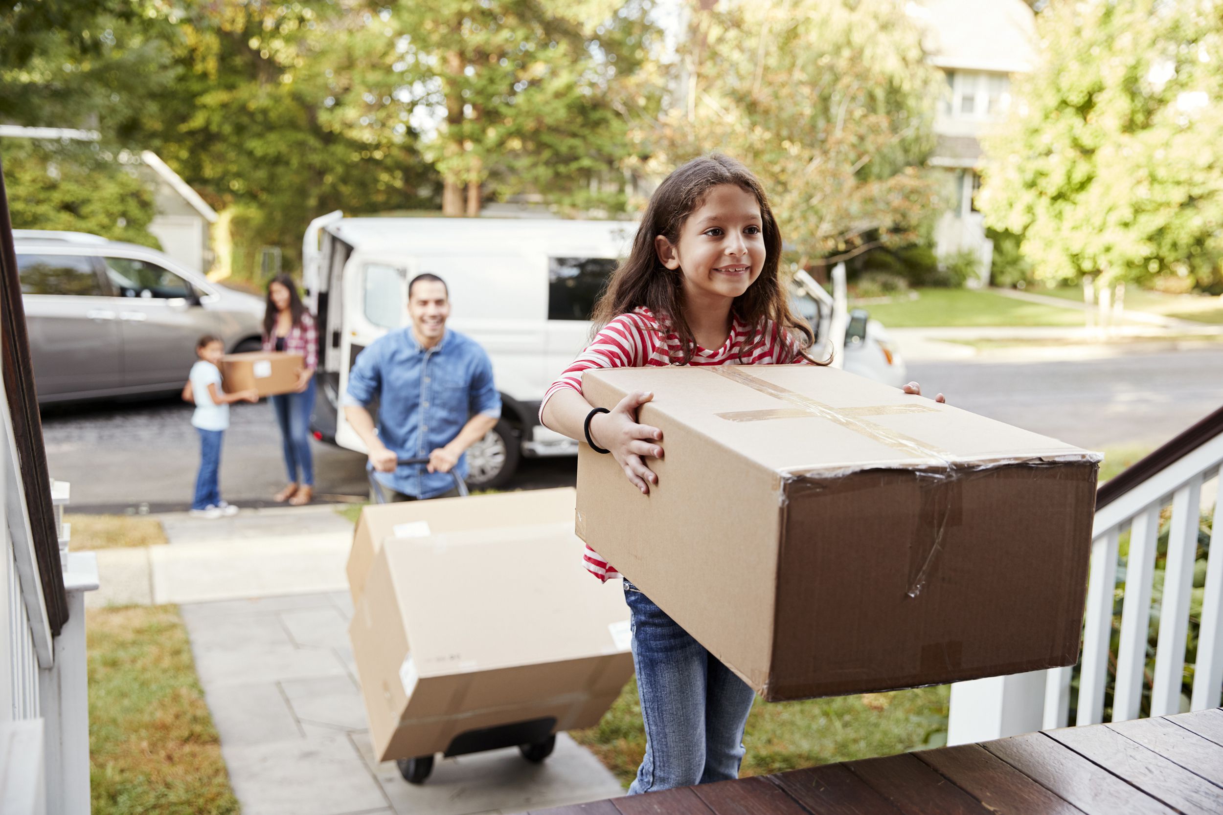 children helping unload boxes from van on family moving in day