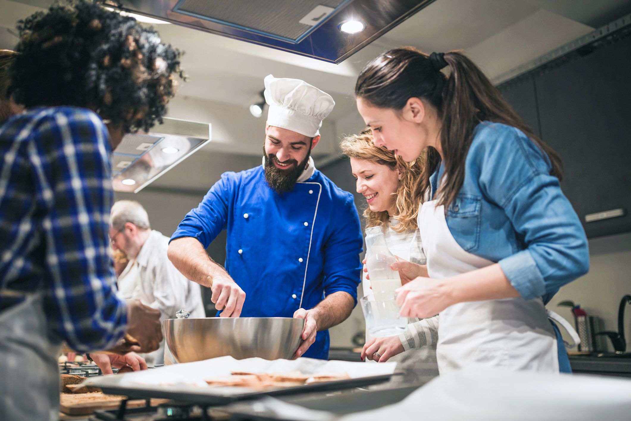cooking class students watching teacher, ingredients on kitchen table
