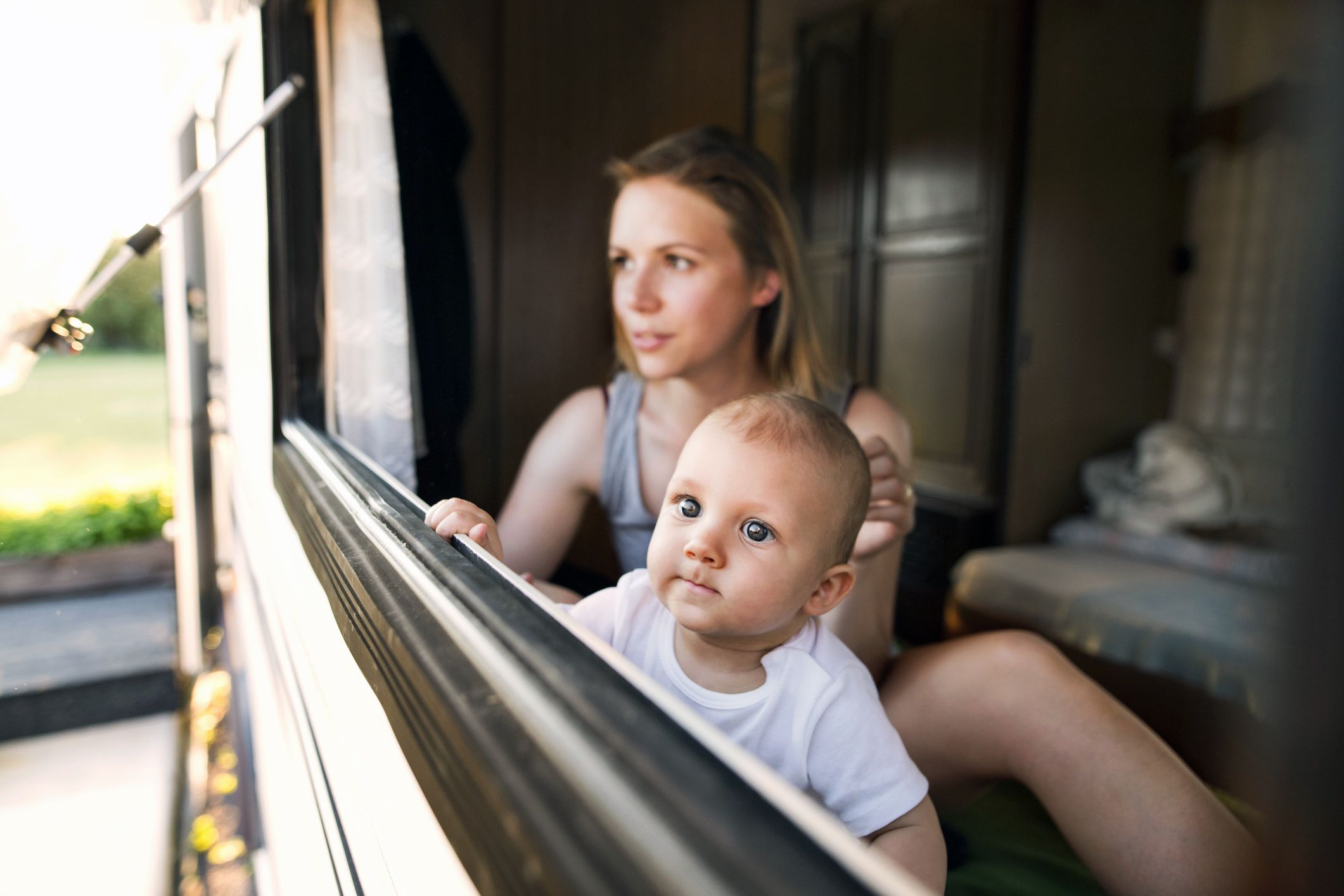 woman and baby looking out camper window
