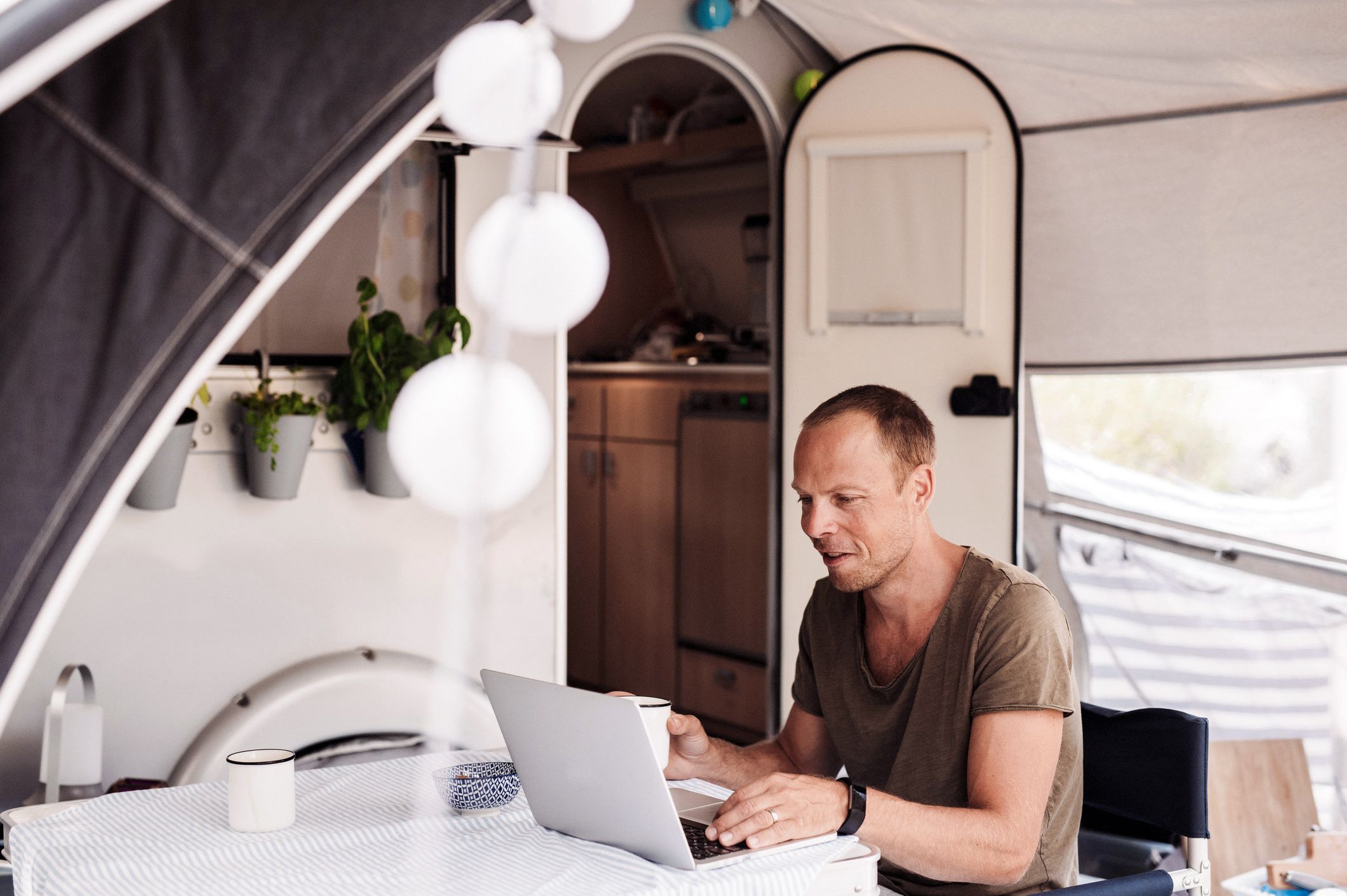 man working at laptop sitting outside rv