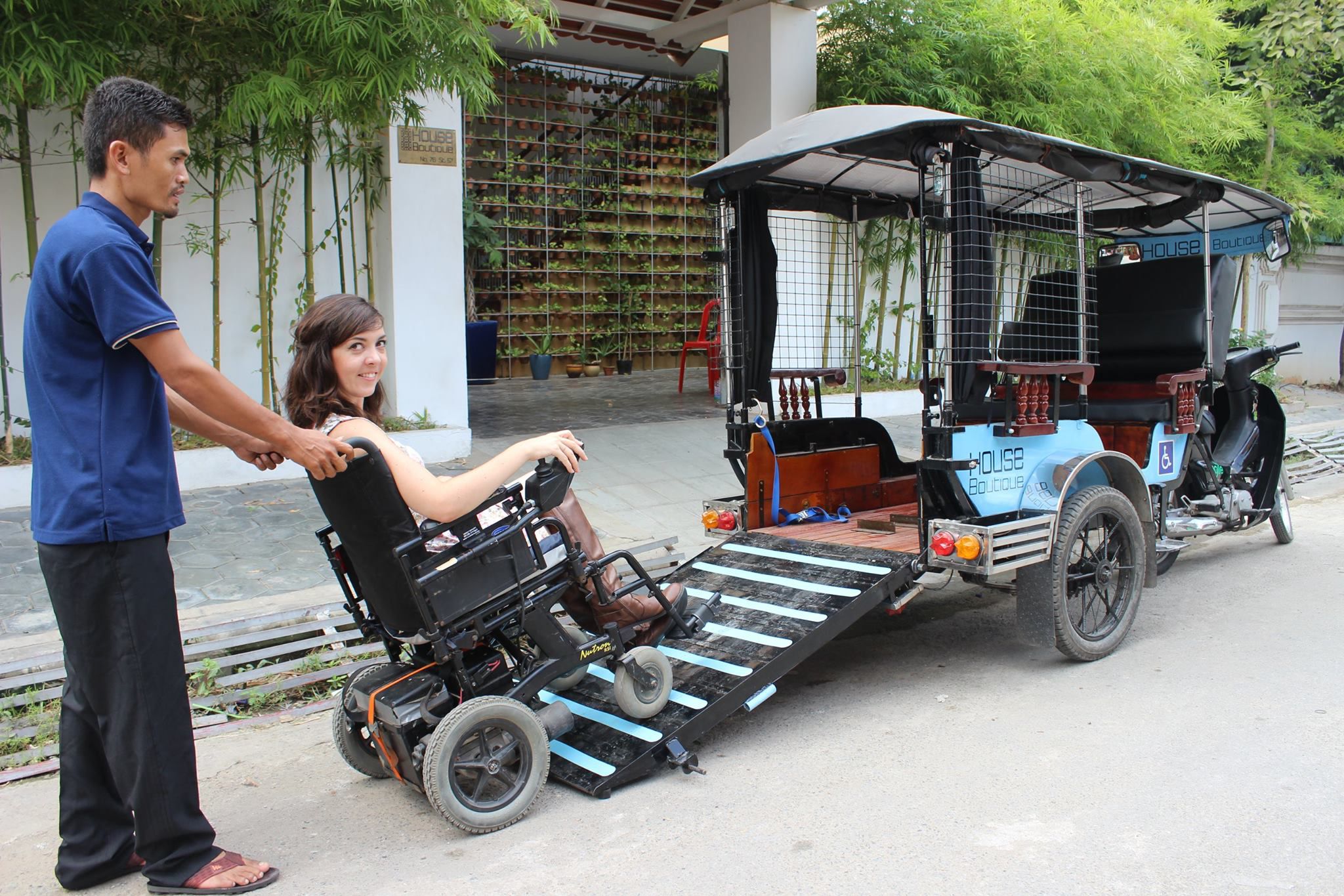 Cambodian man helping a tourist in a wheelchair board a Mobili-tuk taxi
