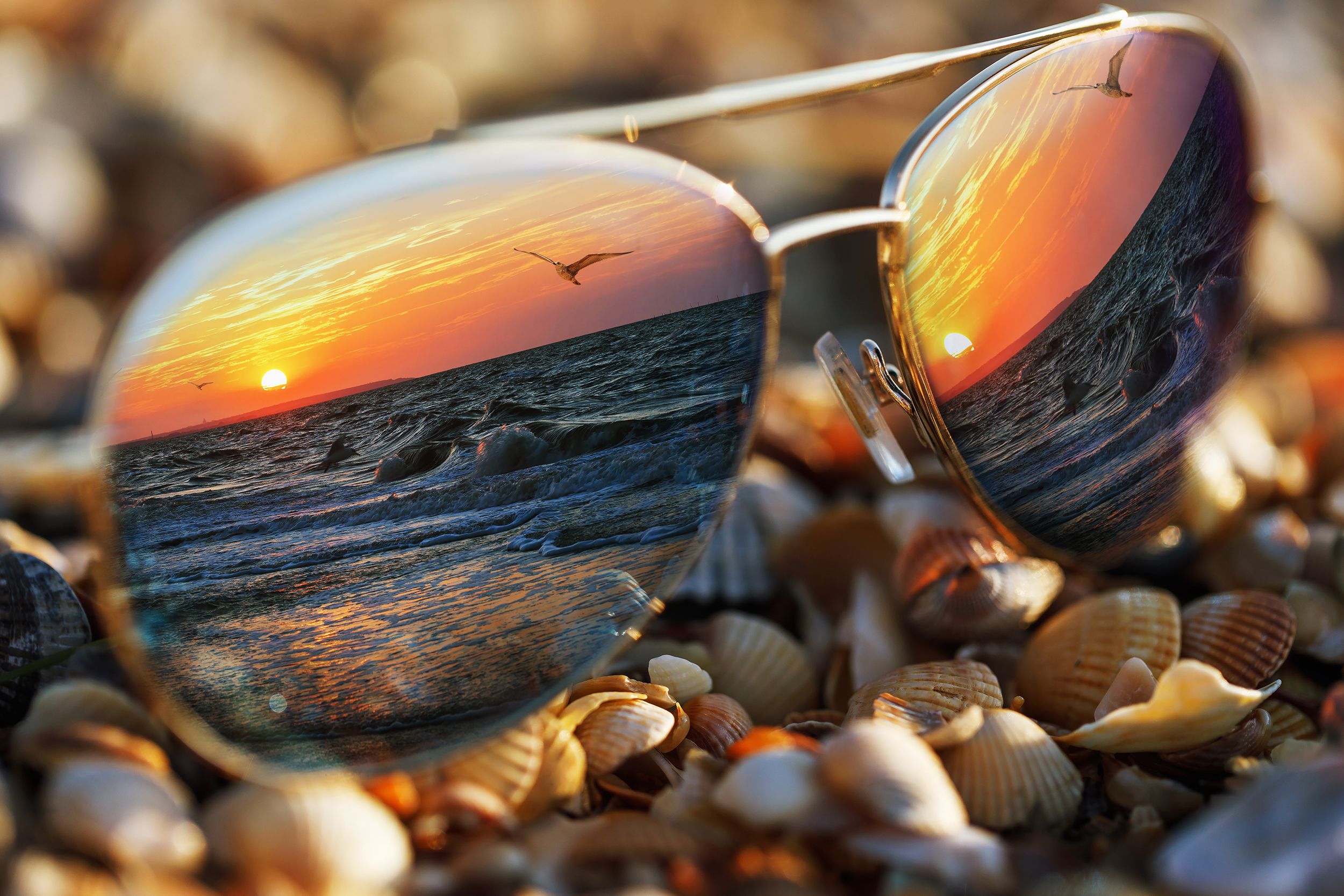 sunglasses on beach with sea reflected in them
