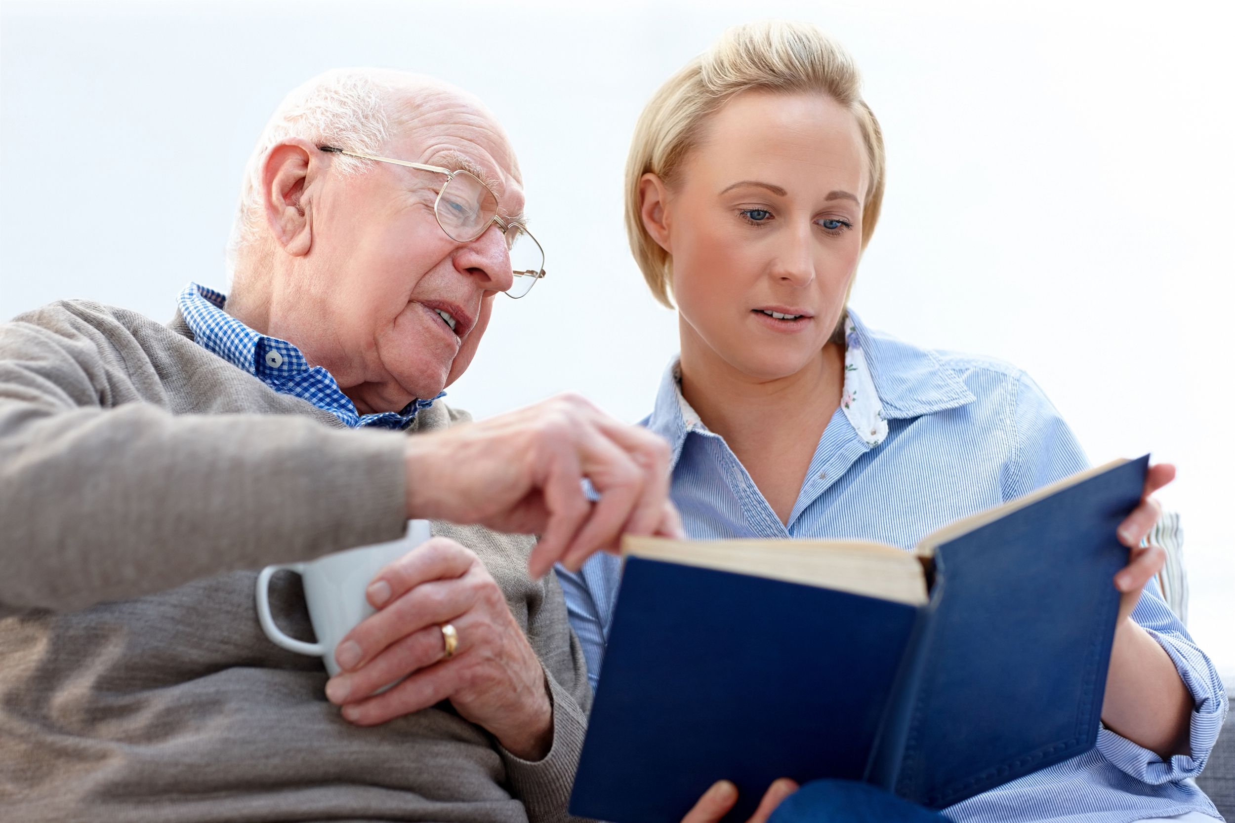 elderly man with female carer reading a book together