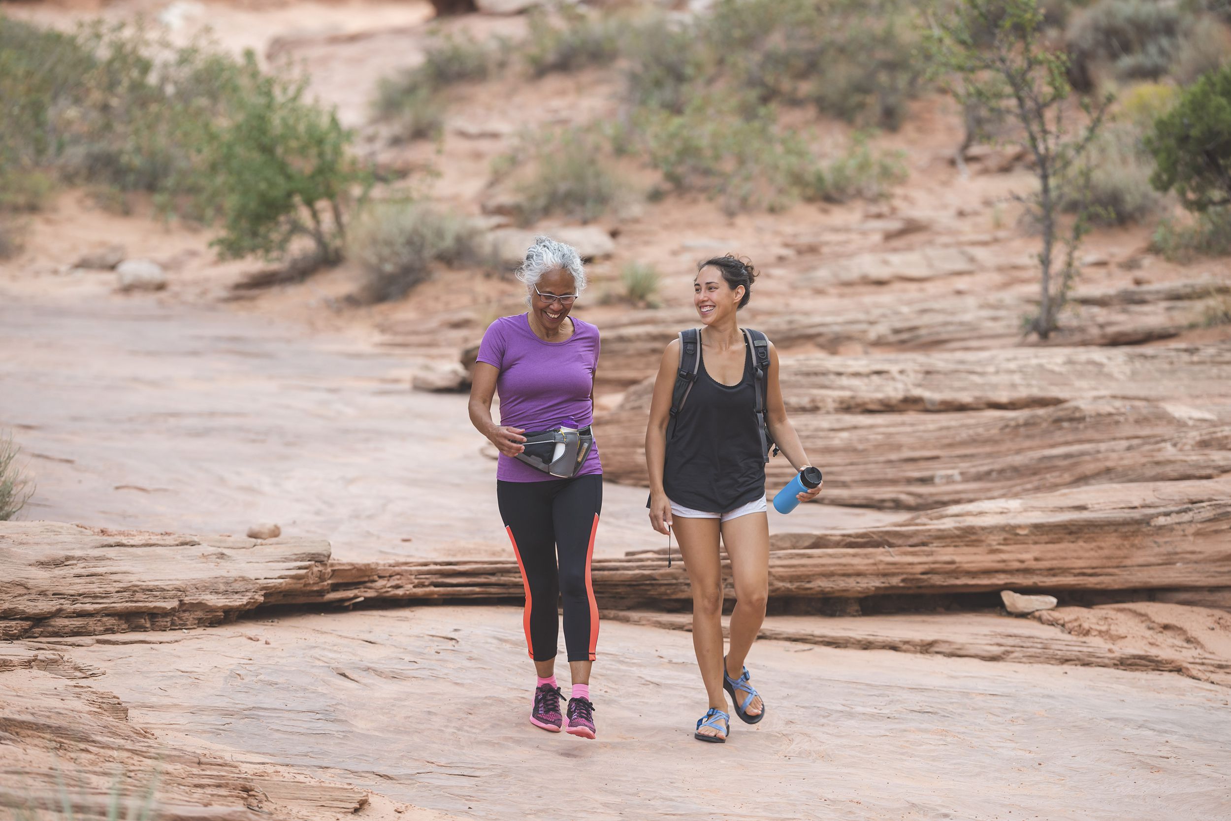 ethnic senior woman hiking with her adult daughter walking in a national park together