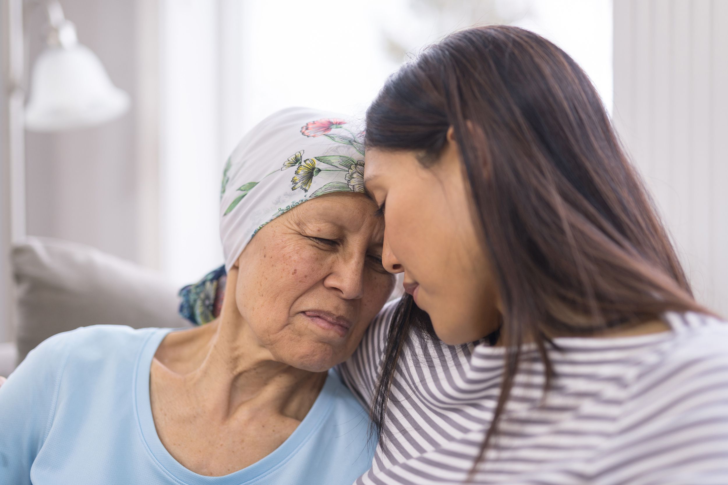 ethnic elderly woman with cancer embracing her adult daughter