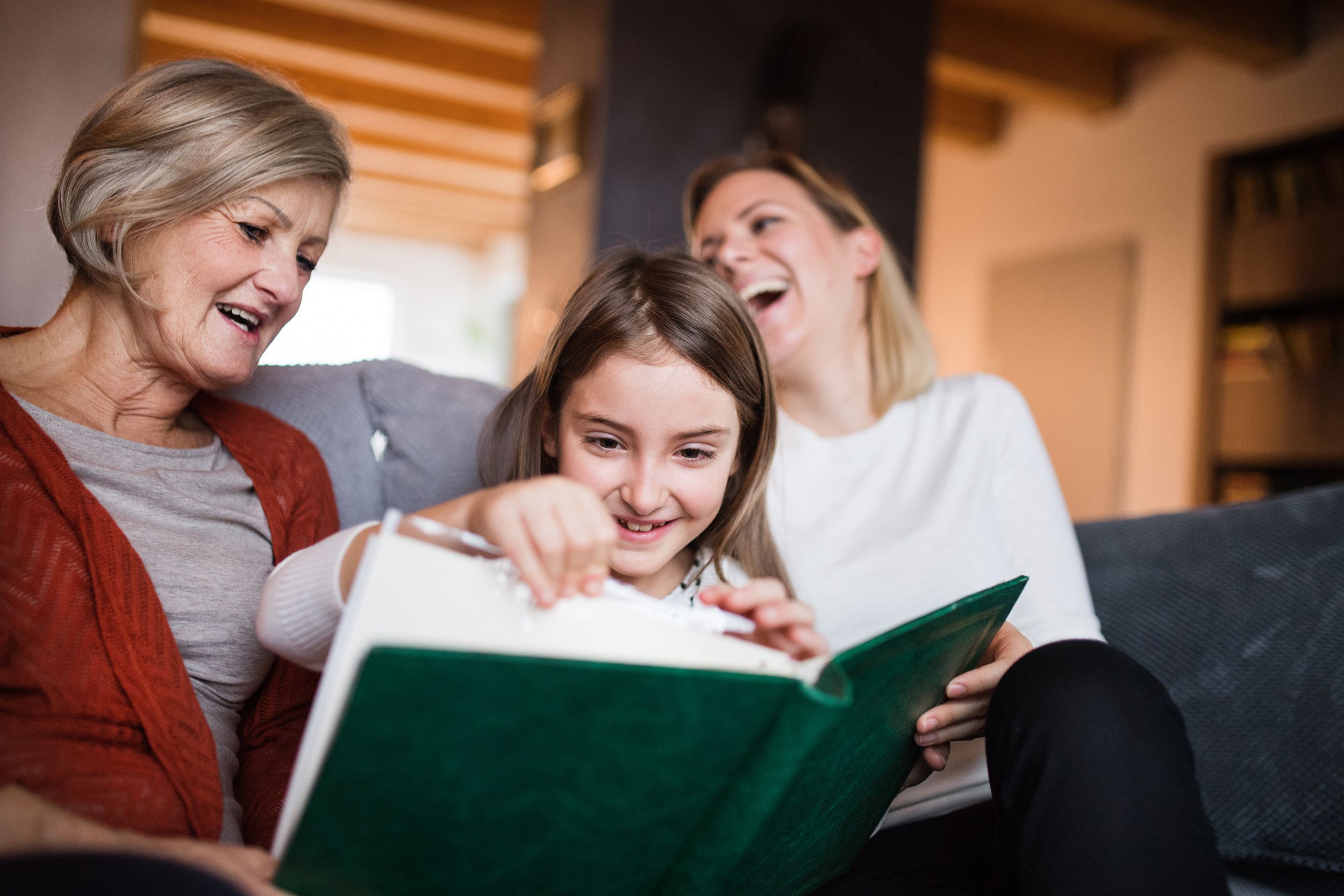 granddaughter with mother and grandmother at home looking at photos