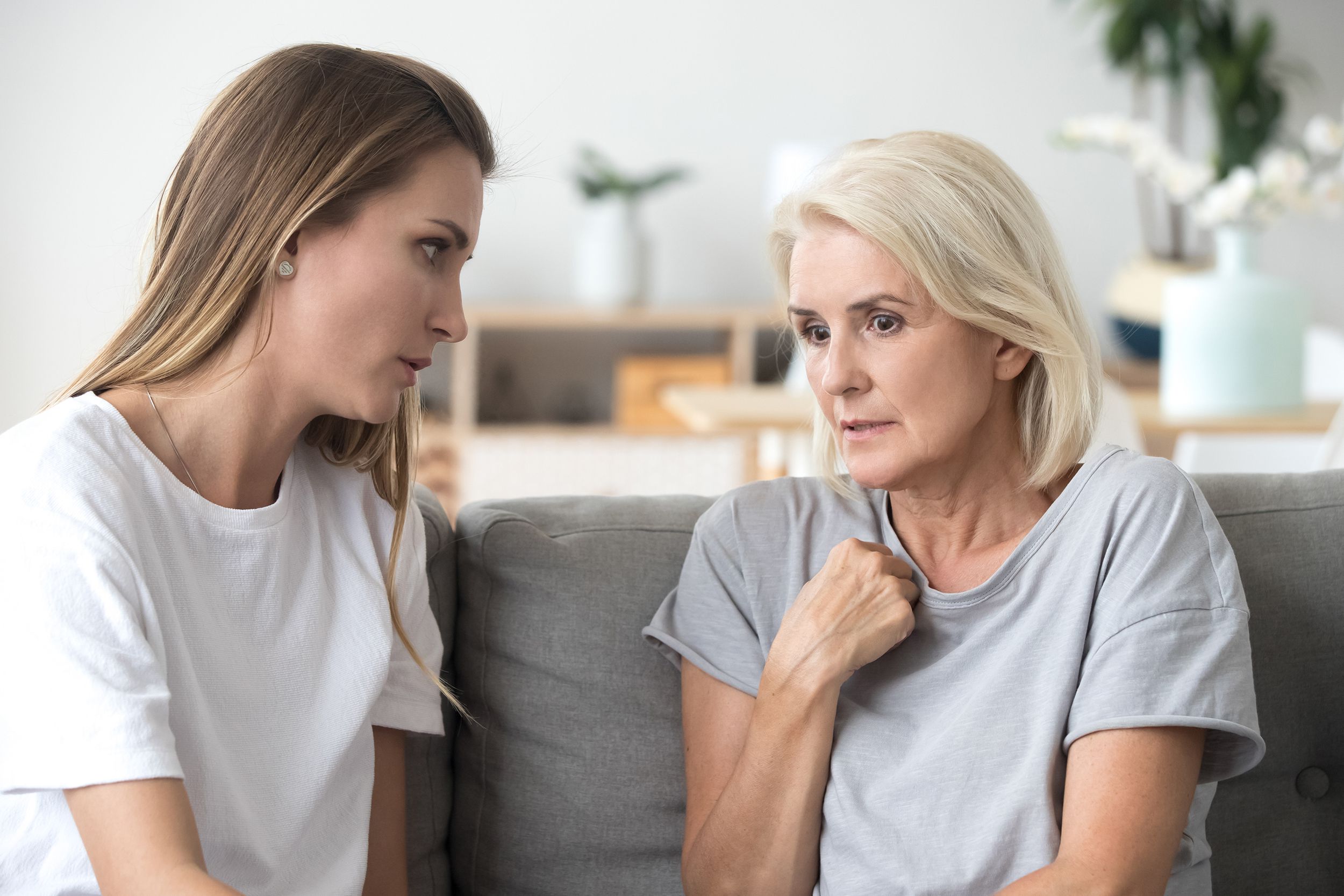 concerned aged mom and adult daughter talk at home