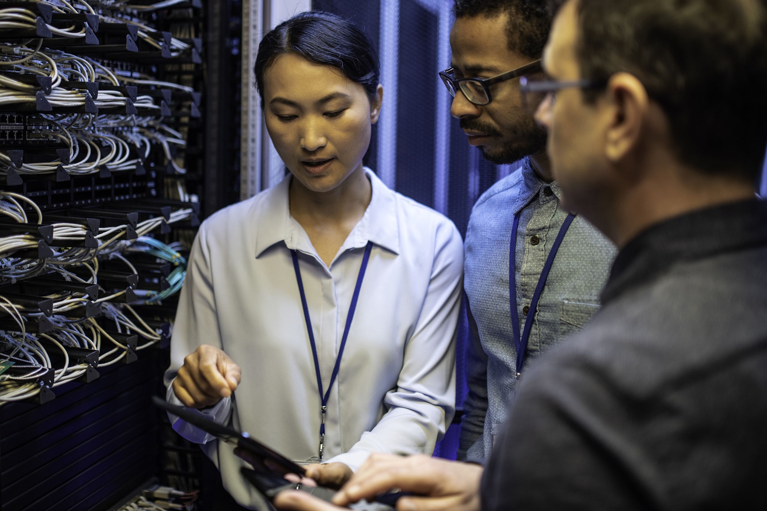 IT engineers looking at a digital tablet next to a server