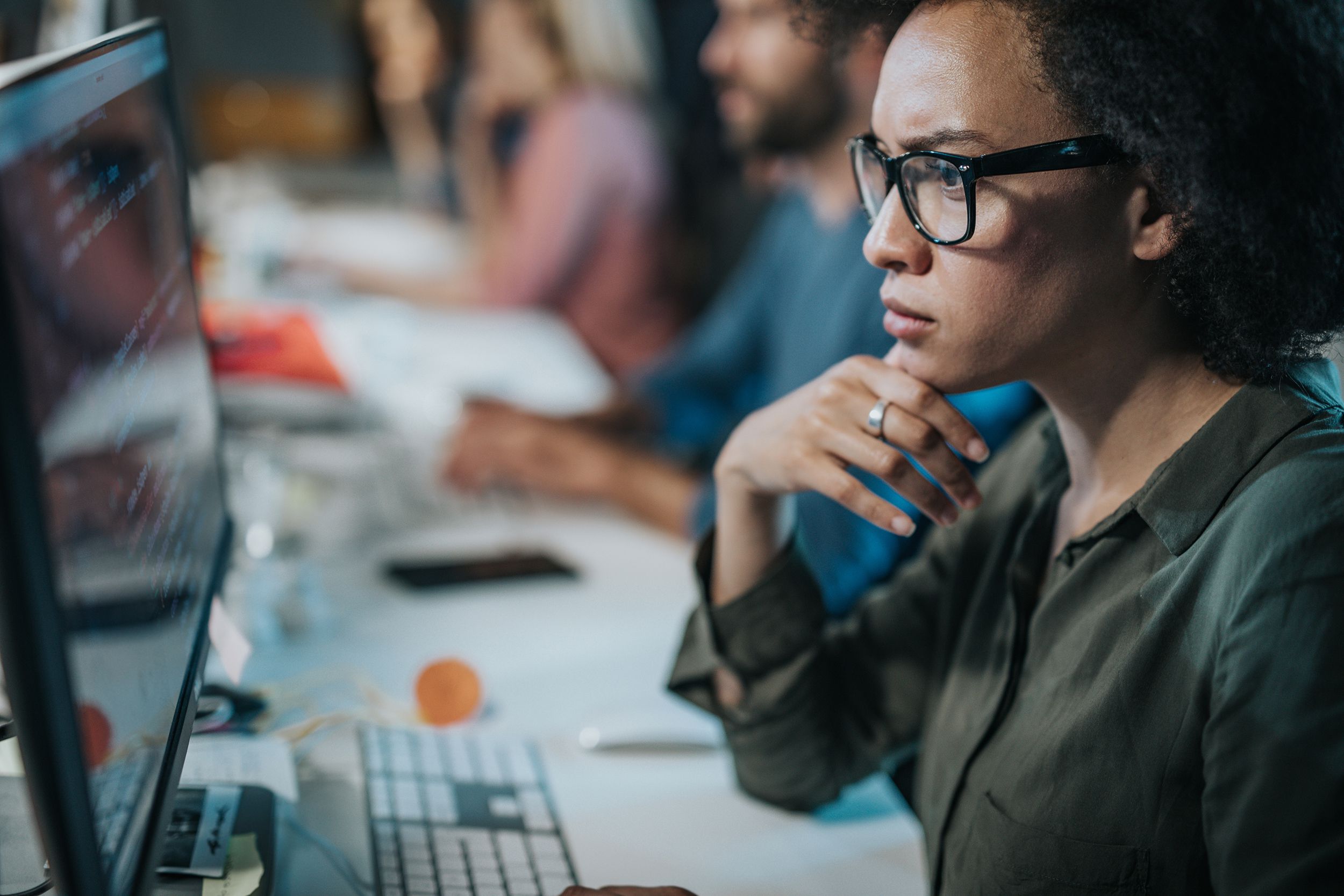 concentrated African American woman brainstorming while coding data on desktop