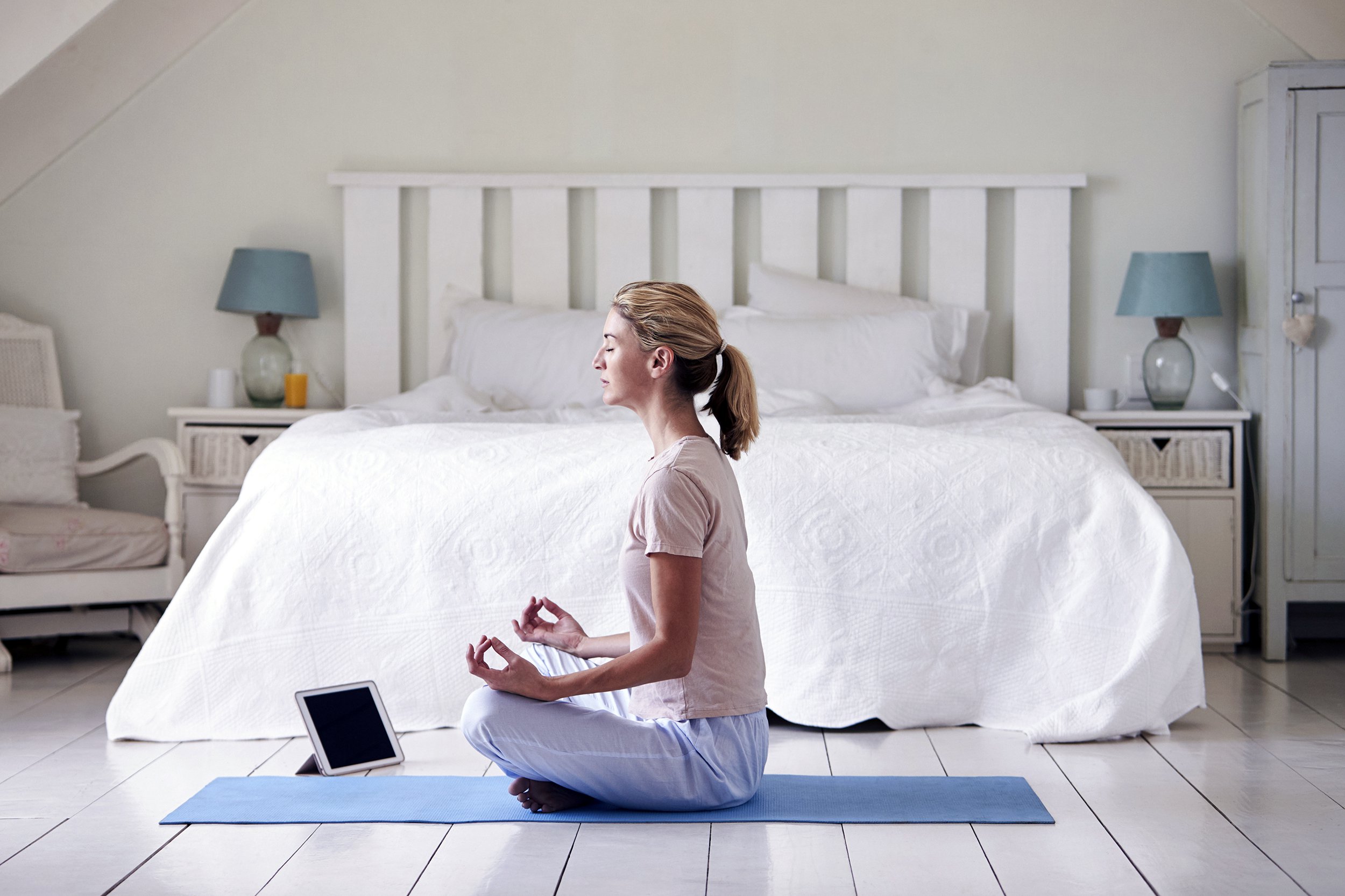 woman with digital tablet using meditation app in bedroom