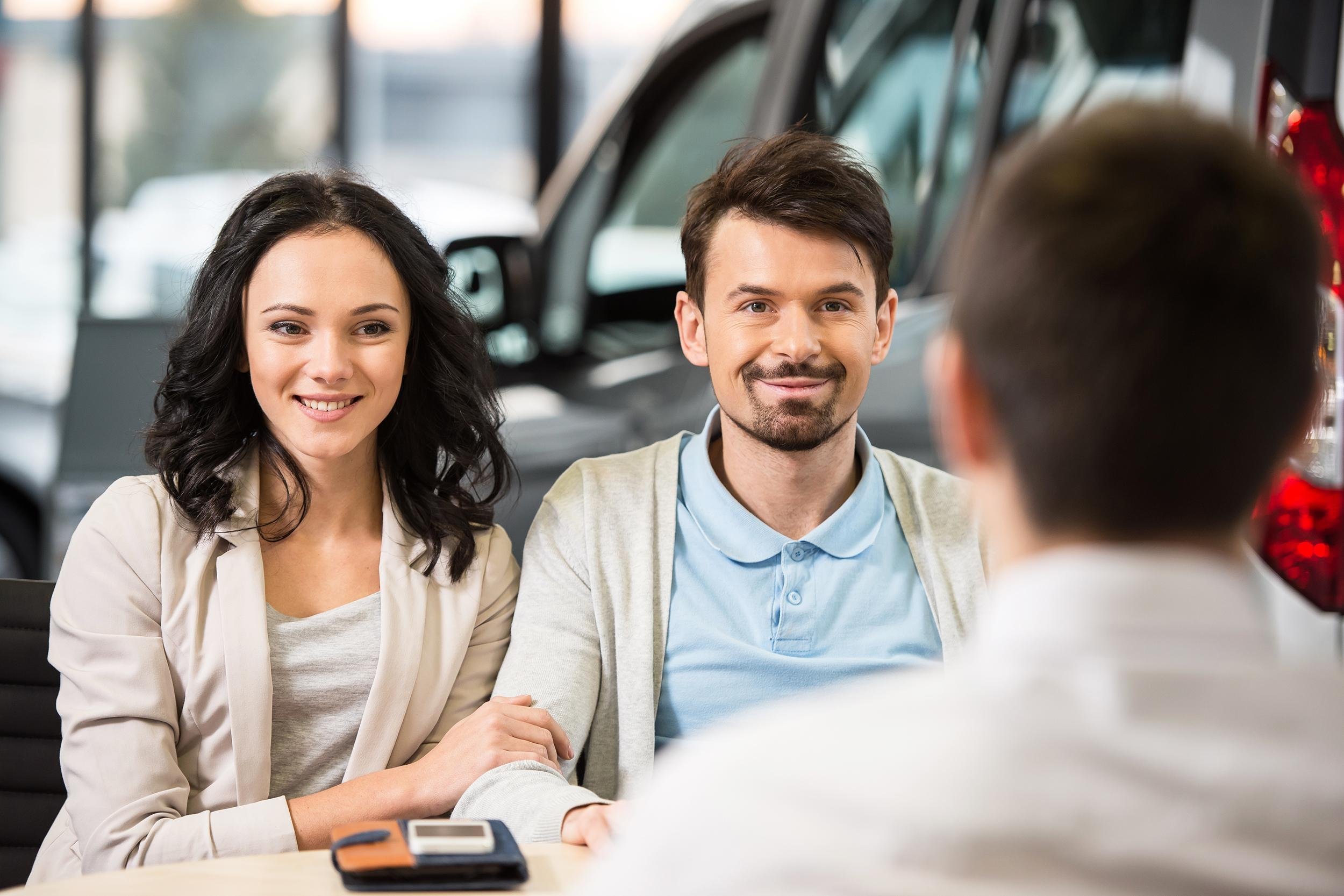 couple sitting down and buying car at dealership