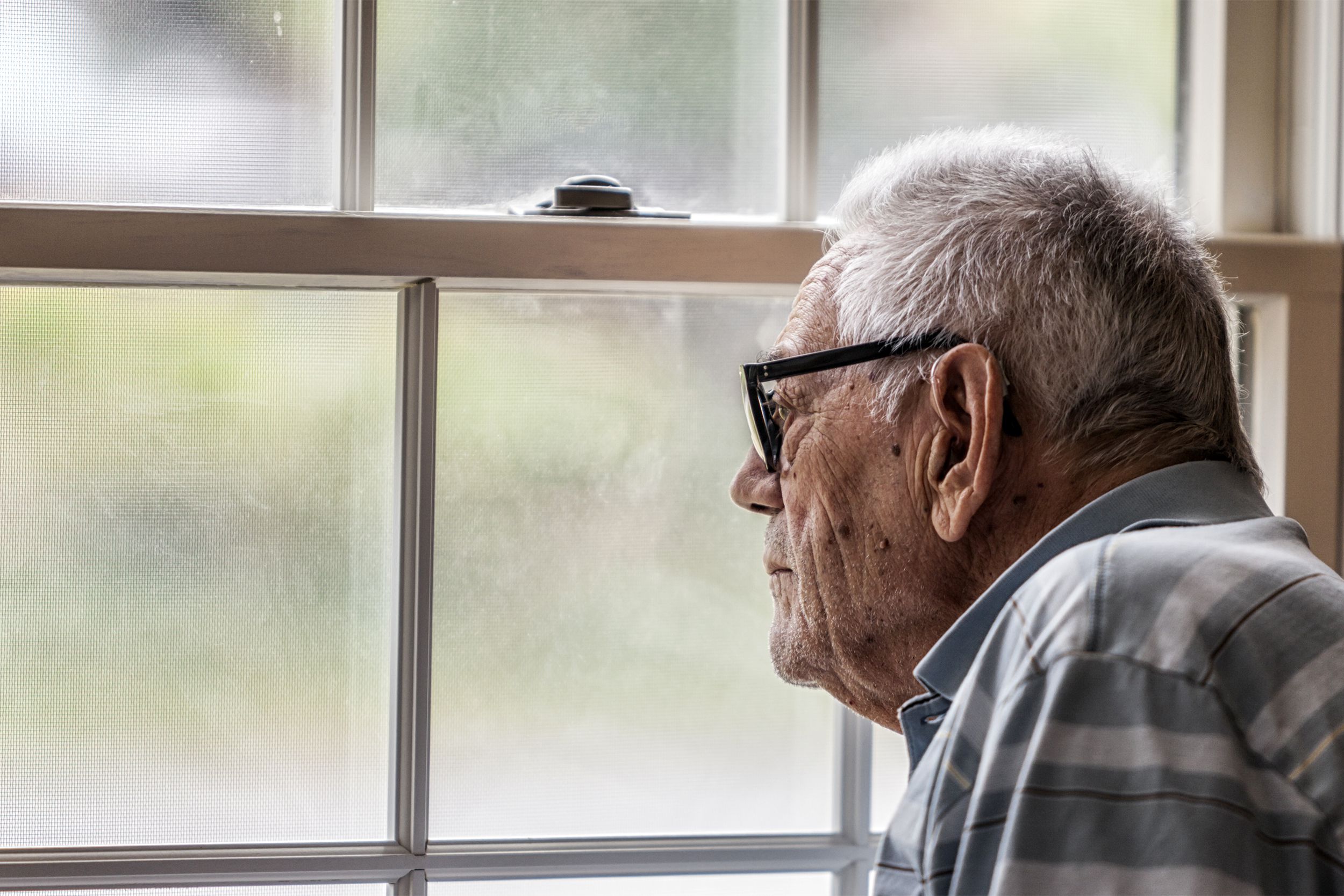 Depressed senior man looking out of window
