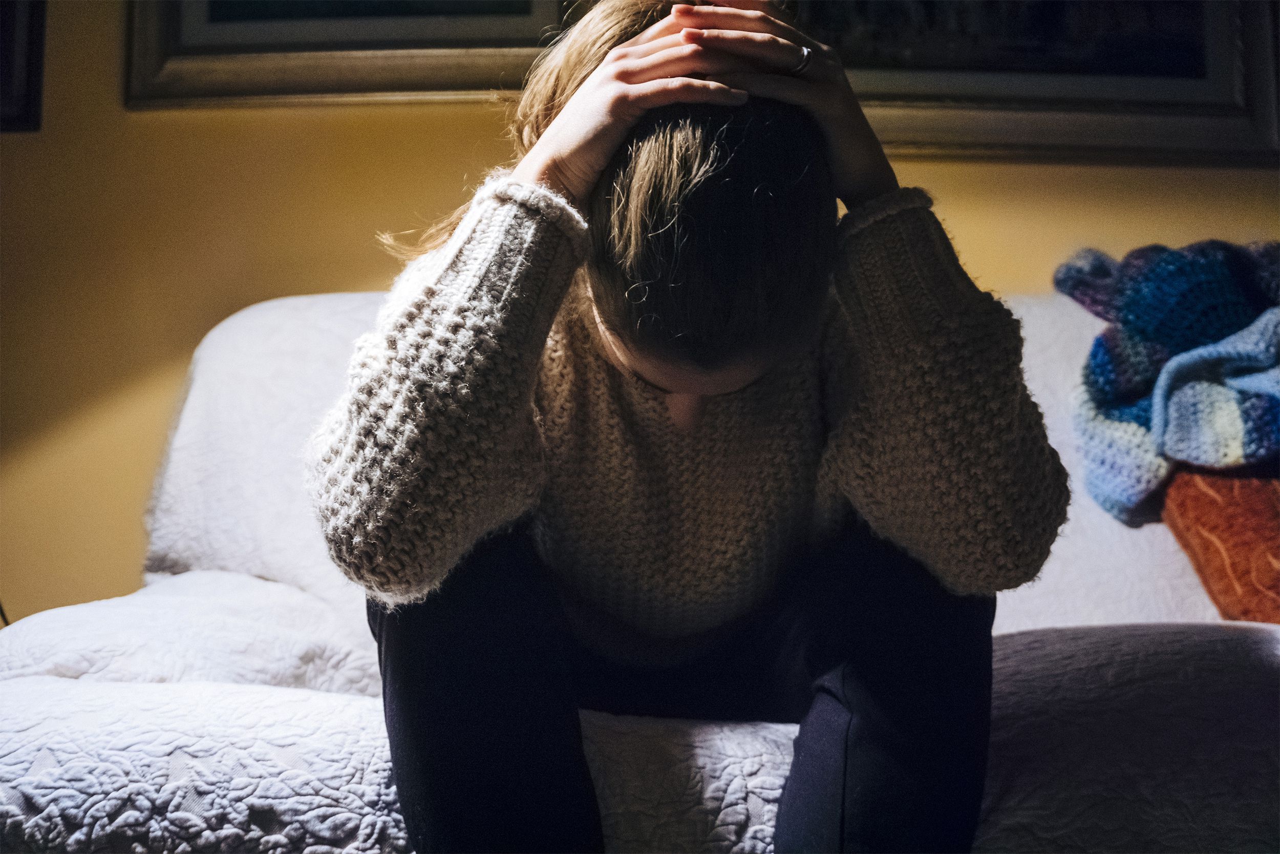 Depressed woman sitting on the edge of her bed