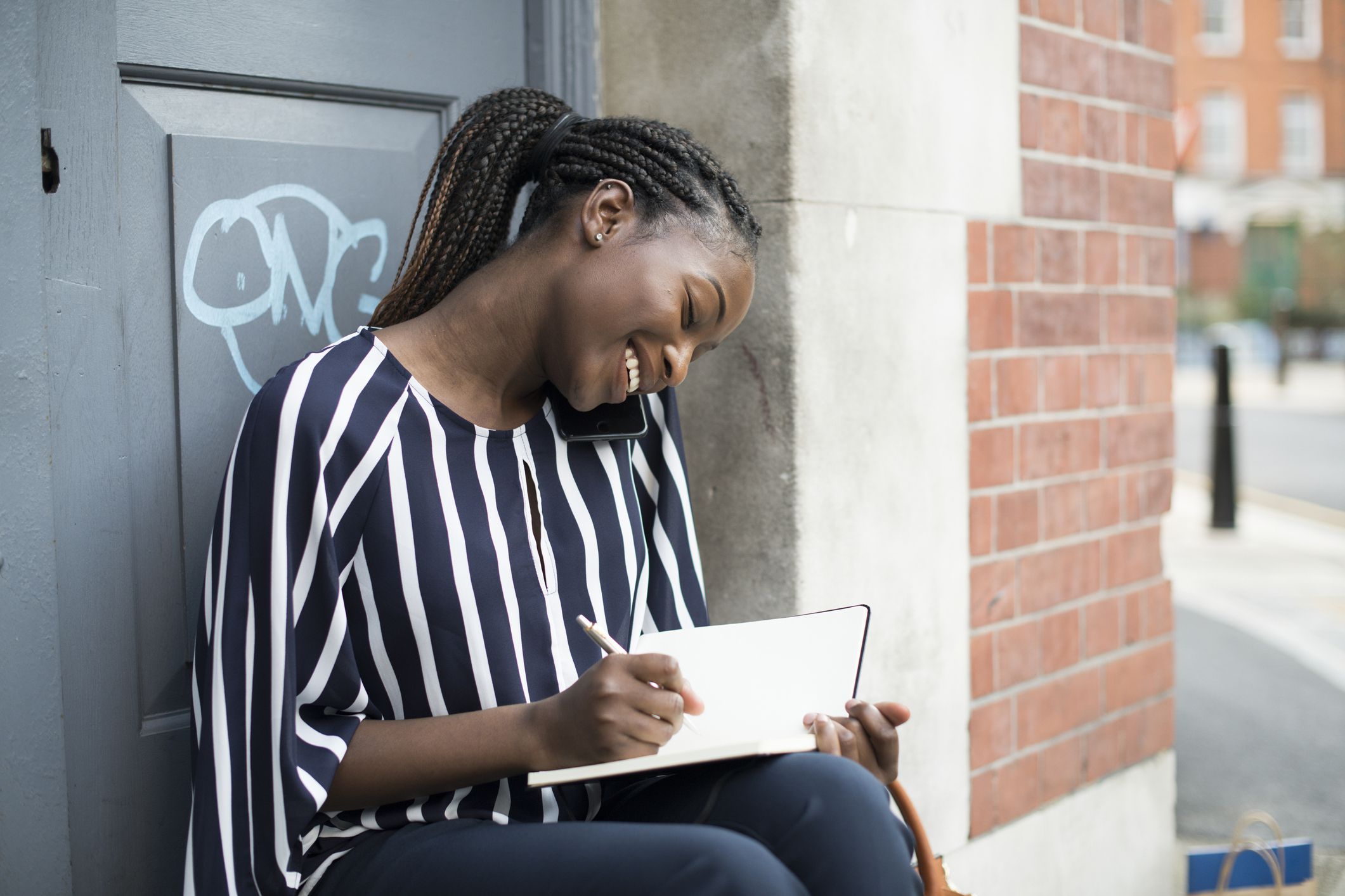 young woman on phone writing in schedule