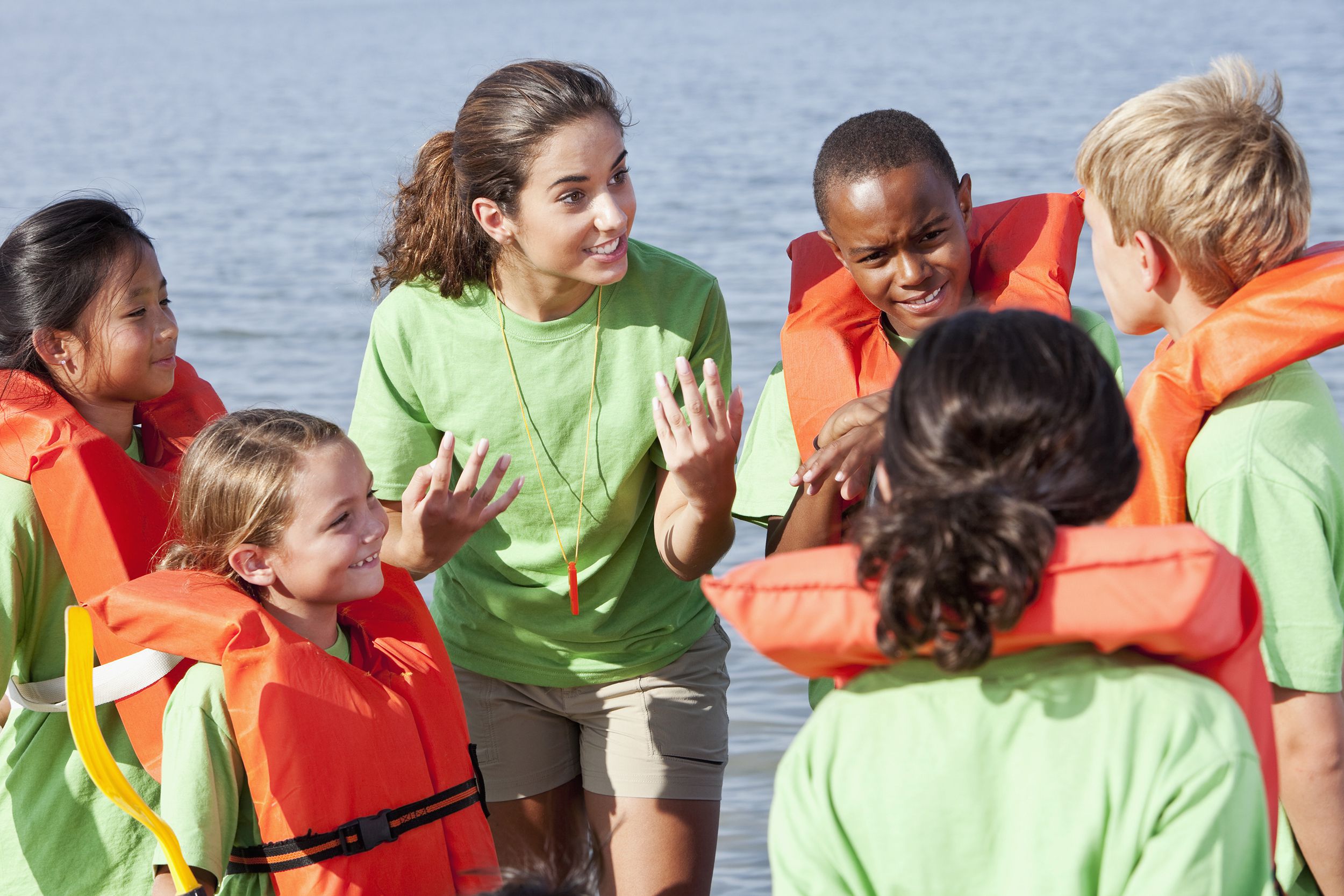 summer camp counselor talking to children wearing life jackets