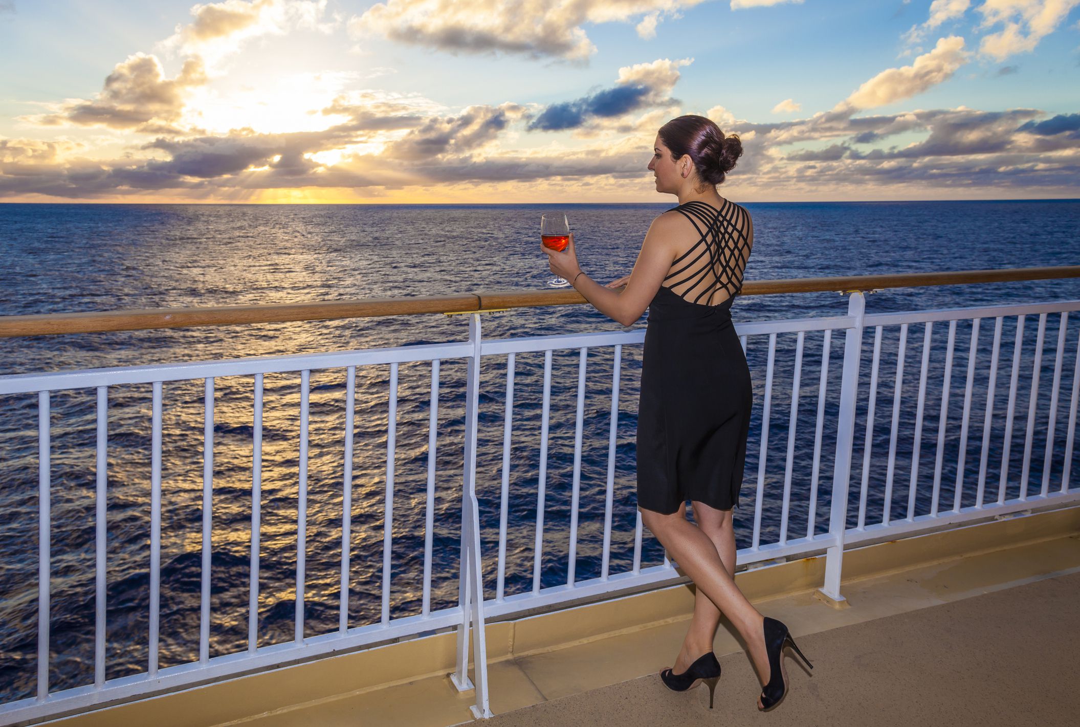 woman in formal dress on cruise deck watching sunset