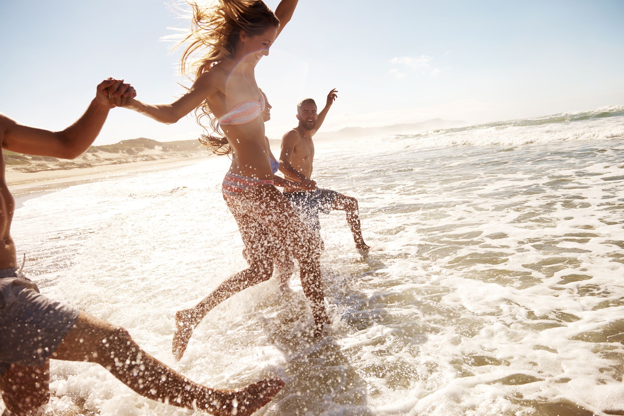 young adults running into the waves of the ocean