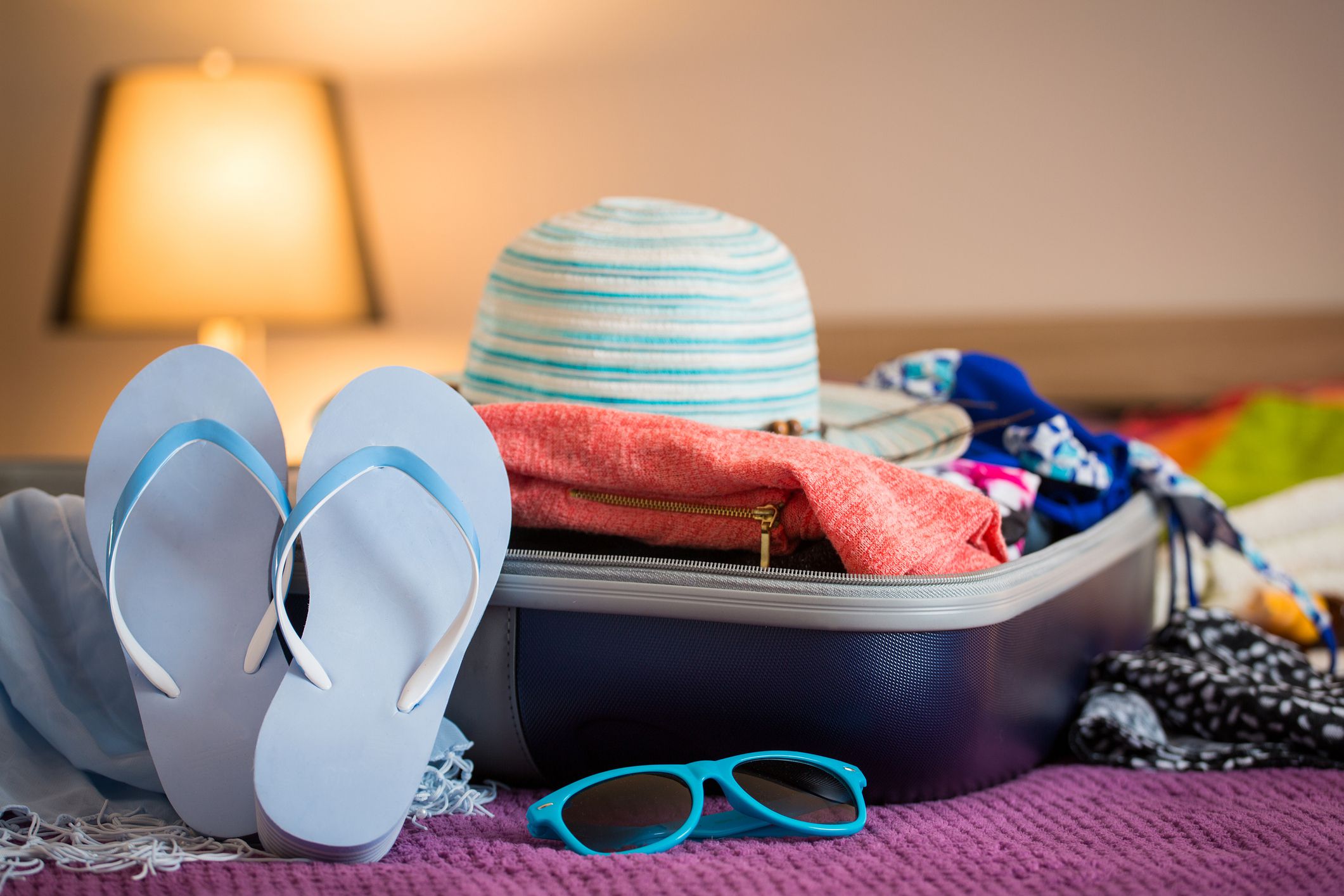 beach supplies in hand luggage on bed