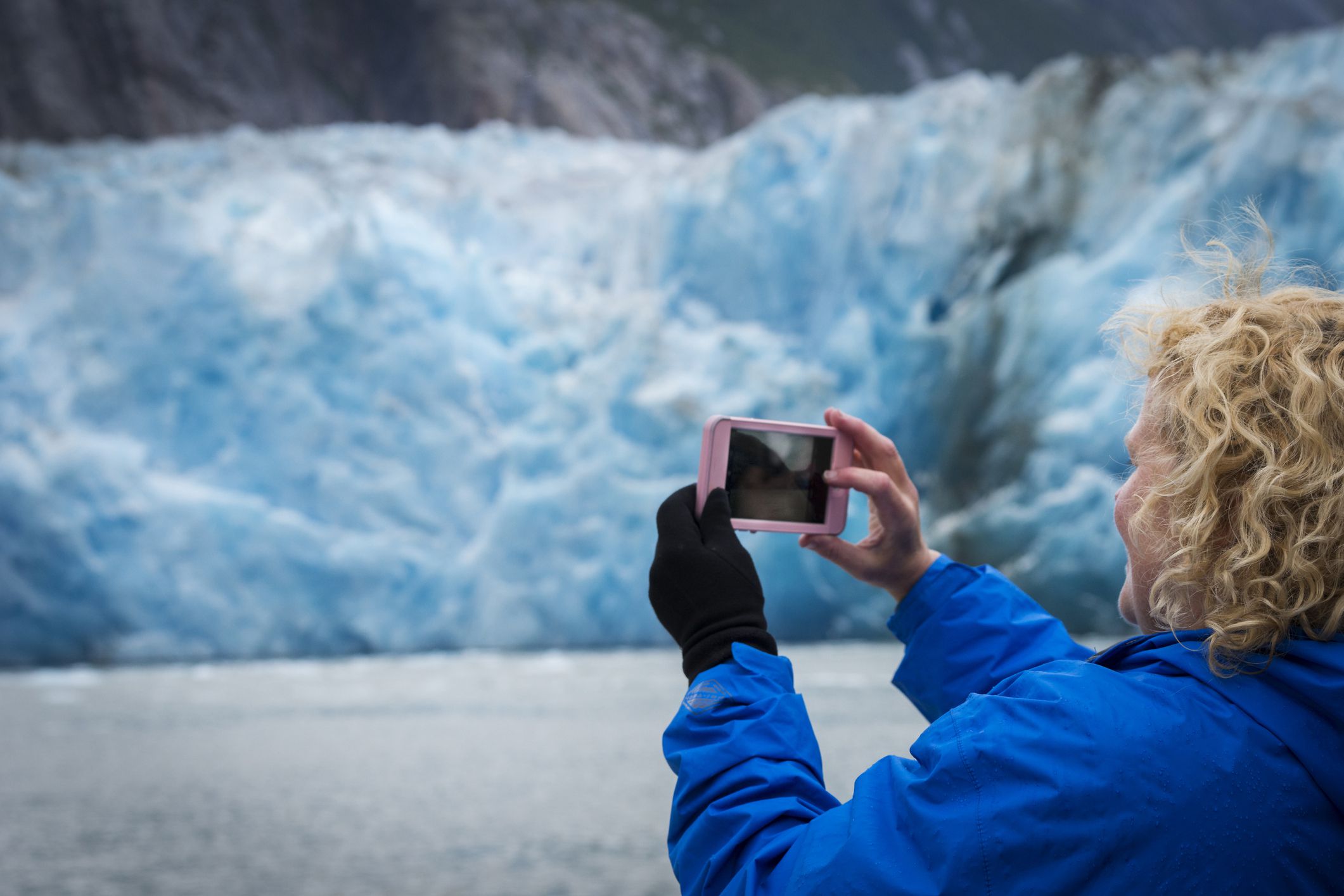 woman taking photo of glacier on cruise
